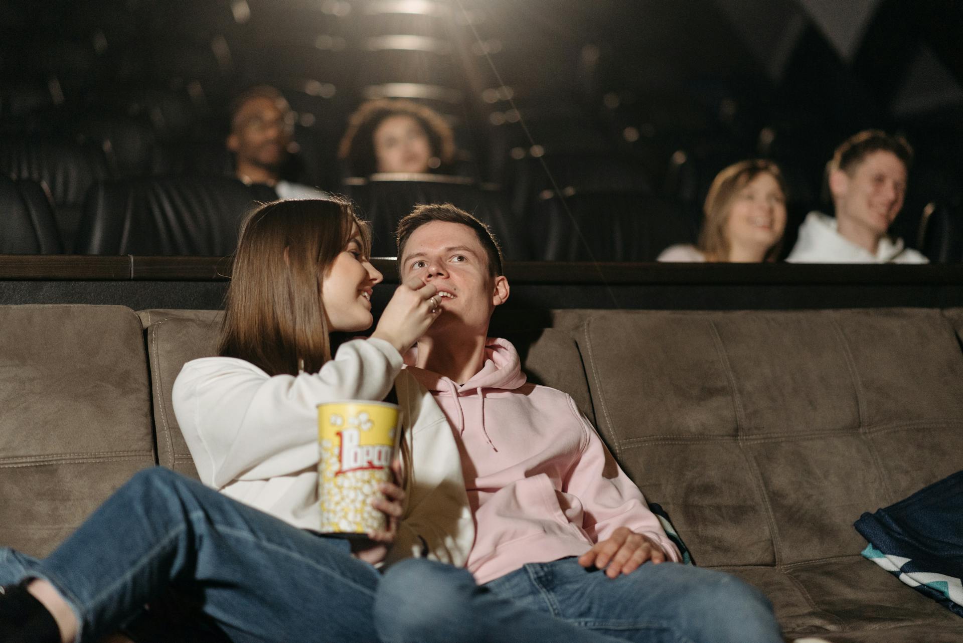 Ein Paar isst Popcorn, während es sich einen Film in einem Kino ansieht | Quelle: Pexels