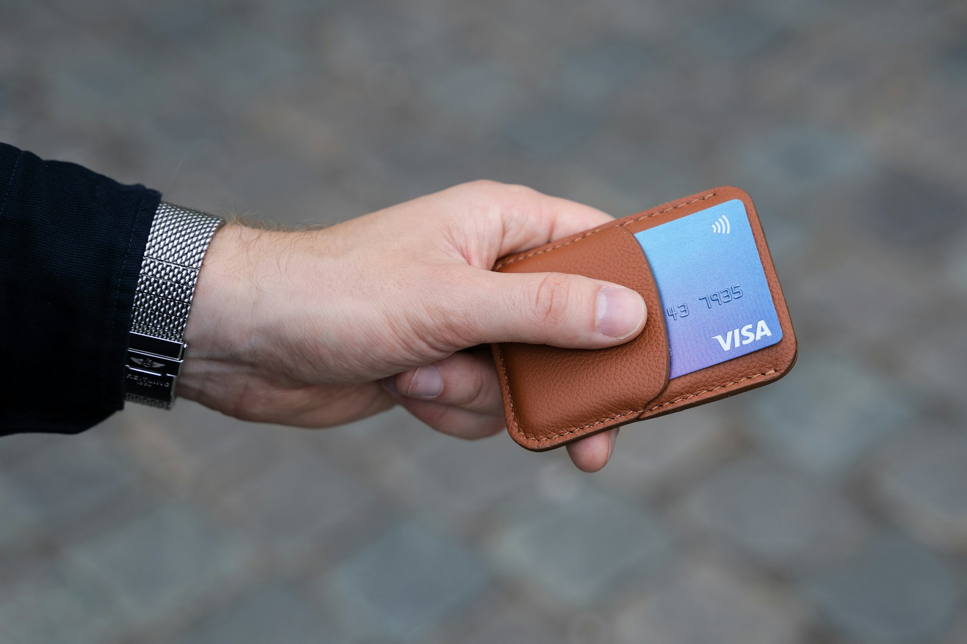 Ein Mann hält eine Bankkarte in einem ledernen Kartenhalter | Quelle: Unsplash