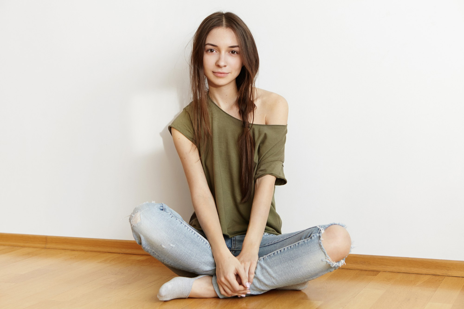 Ein fröhliches Teenager-Mädchen, das auf dem Boden sitzt und lächelt | Quelle: Freepik
