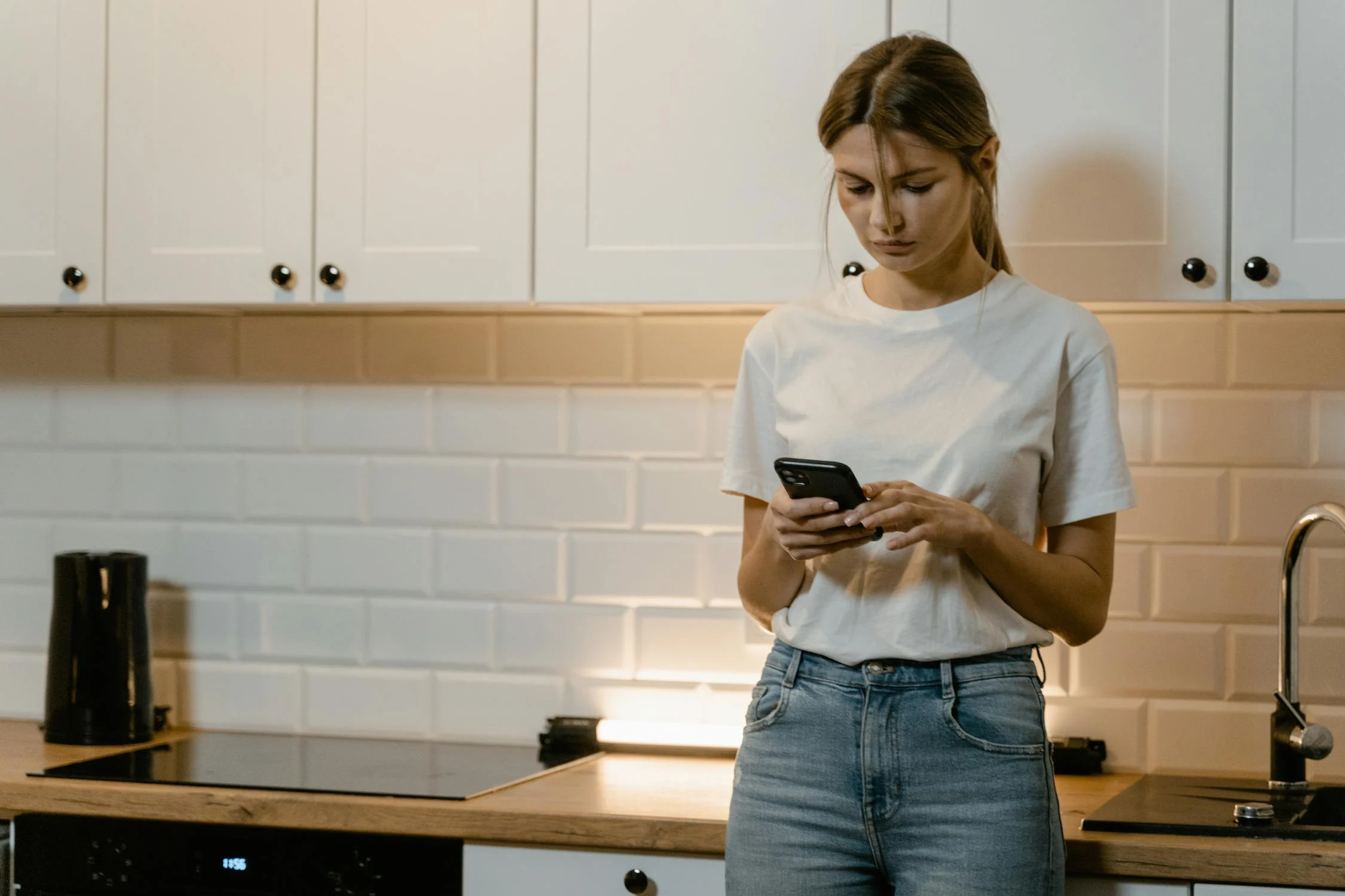 Eine Frau, die in ihrer Küche auf ihrem Handy tippt | Quelle: Pexels