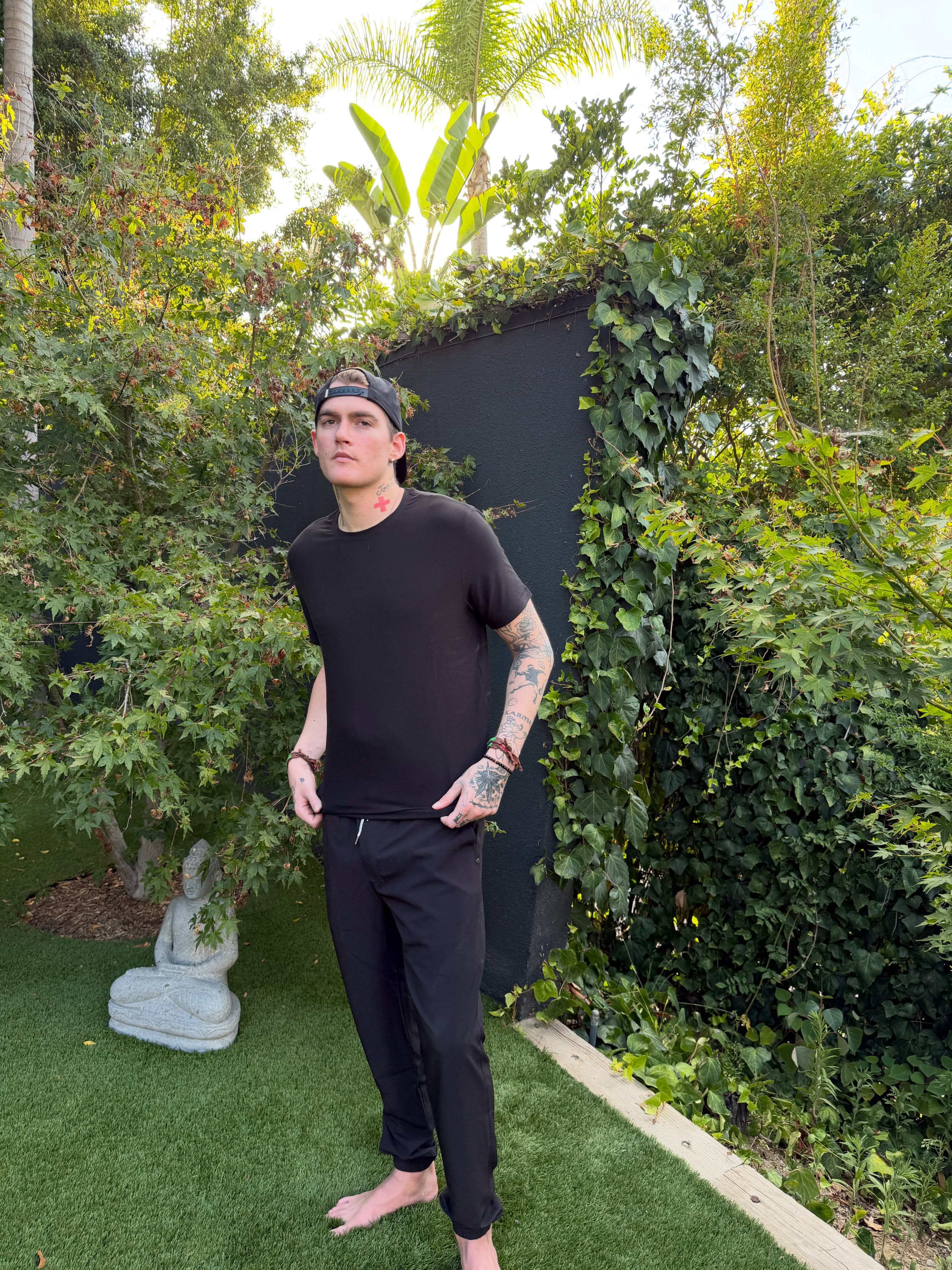 Presley Gerber steht ganz lässig auf dem üppigen Rasen im Garten und rückt sein Outfit zurecht – so sieht man ihn in einem Bild aus seinem letzten Social-Media-Post. | Quelle: Instagram/presleygerber