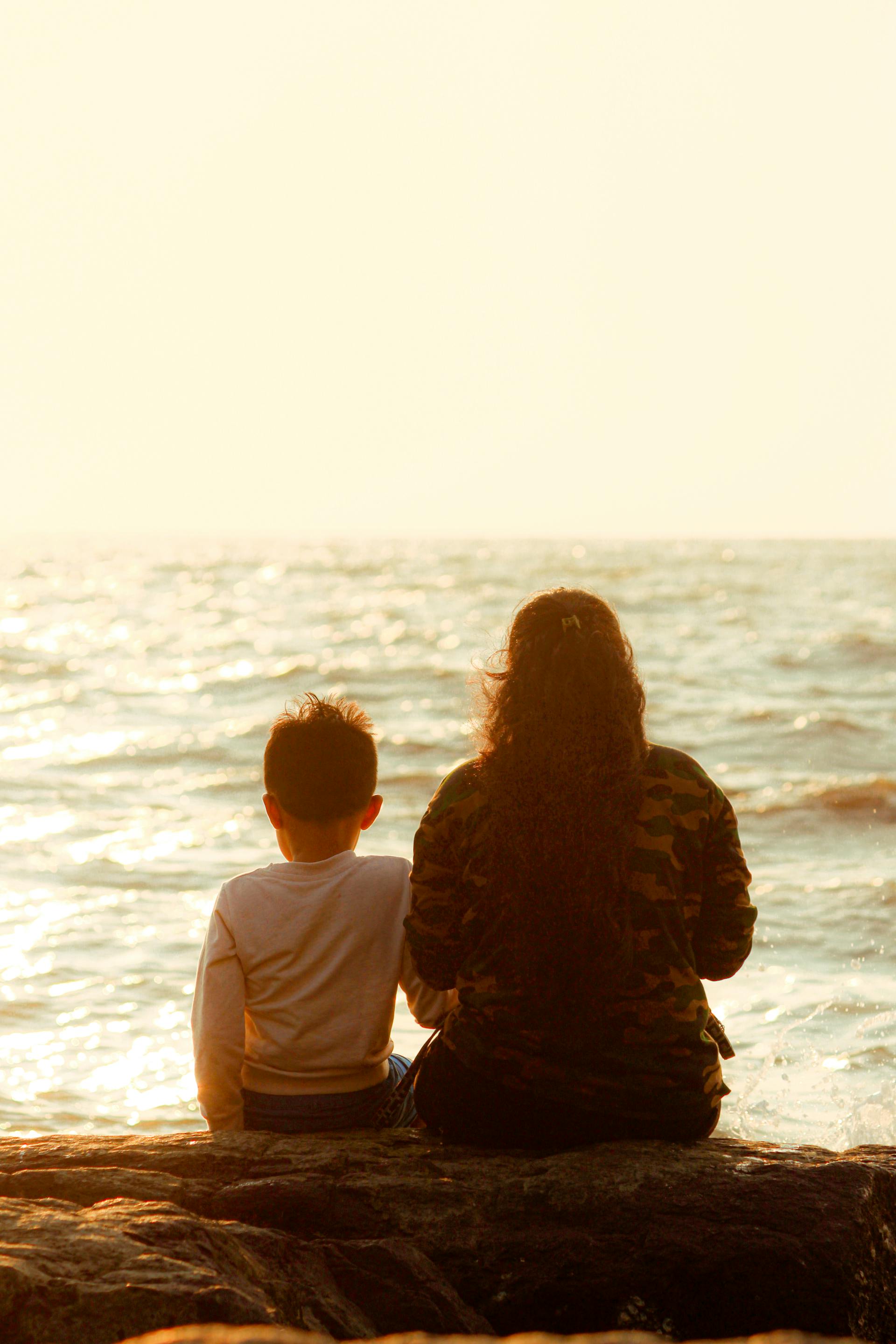 Eine Mutter sitzt mit ihrem Sohn am Meeresstrand | Quelle: Pexels