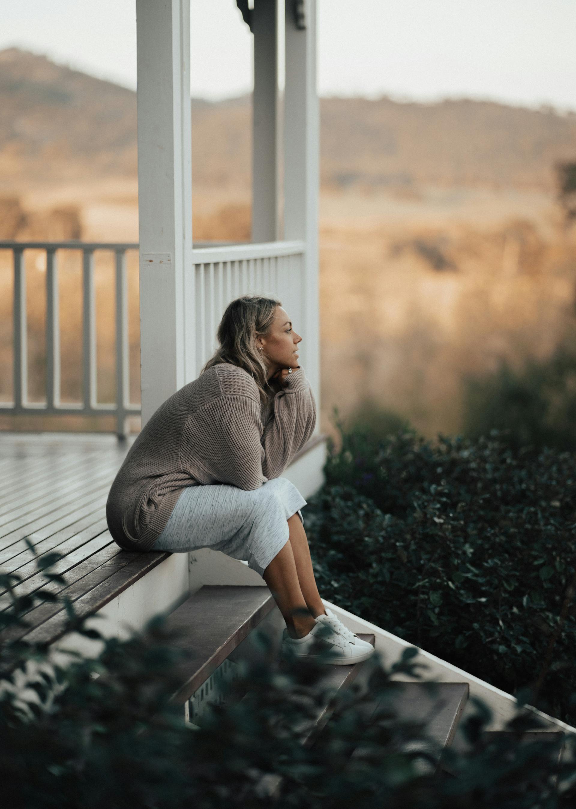Eine Frau sitzt auf der Veranda ihres Hauses | Quelle: Pexels