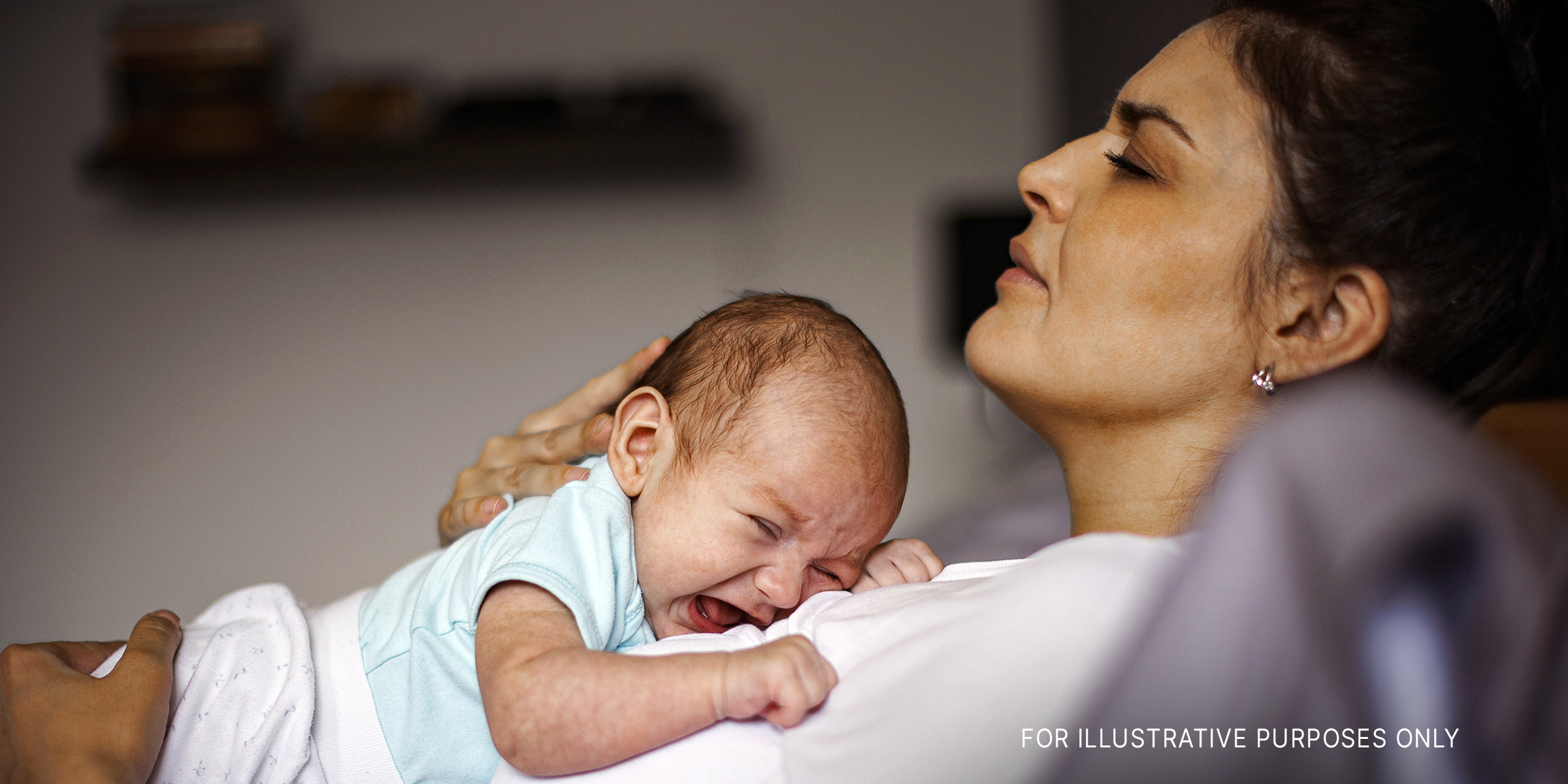 Eine verzweifelte Frau, die sich mit ihrem weinenden Baby auf die Brust legt | Quelle: Getty Images