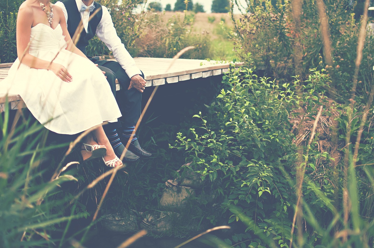 Braut und Bräutigam sitzen auf einer Brücke | Quelle: Pixabay