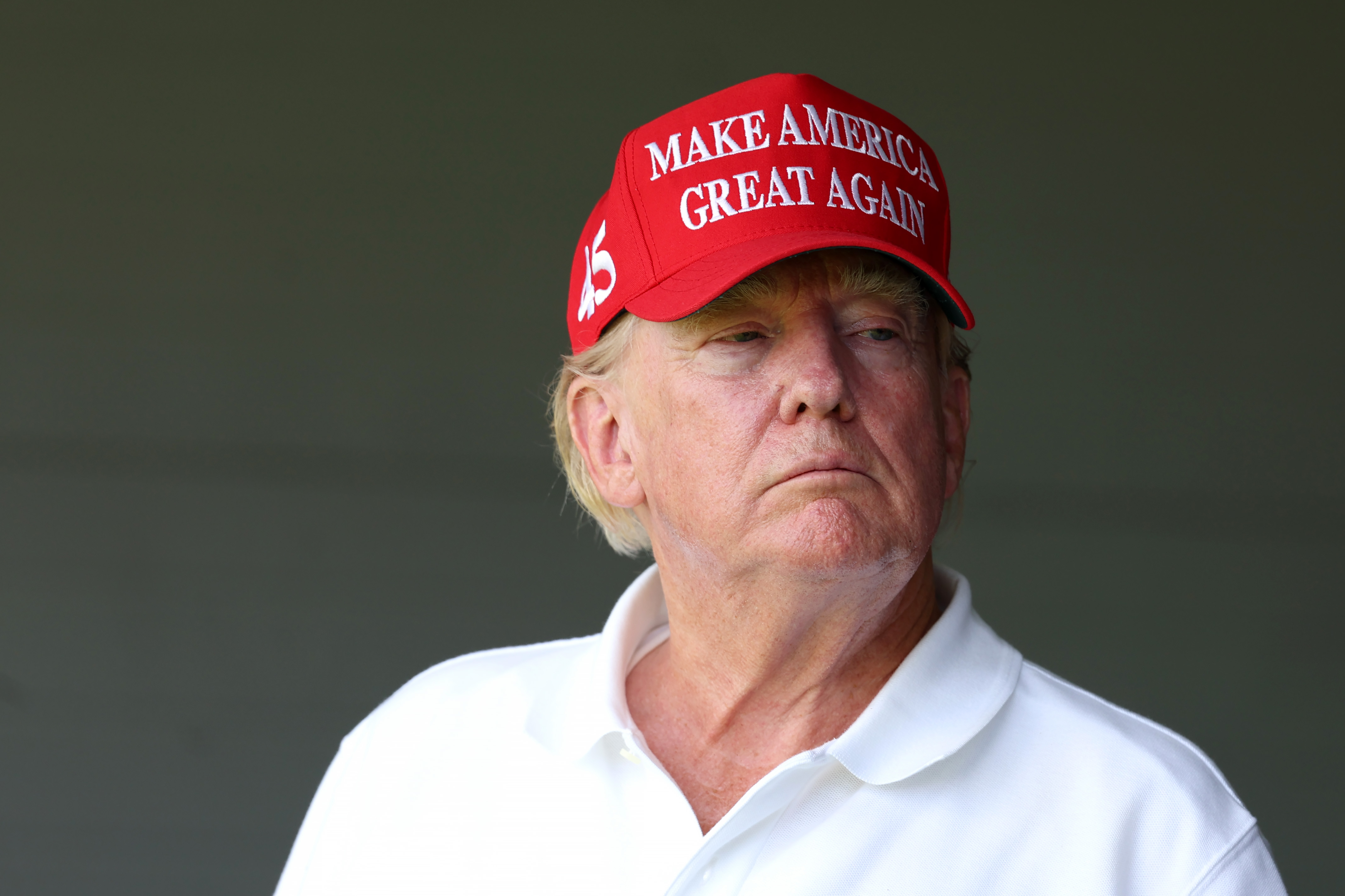 Am 26. Mai schaut Donald Trump mit demselben roten Hut und weißen Hemd aus einem schattigen Bereich zu. Sein Hautton sieht im gedämpften Licht gleichmäßiger aus, obwohl die rote Färbung im Bereich seiner Wangen immer noch stark ausgeprägt ist.