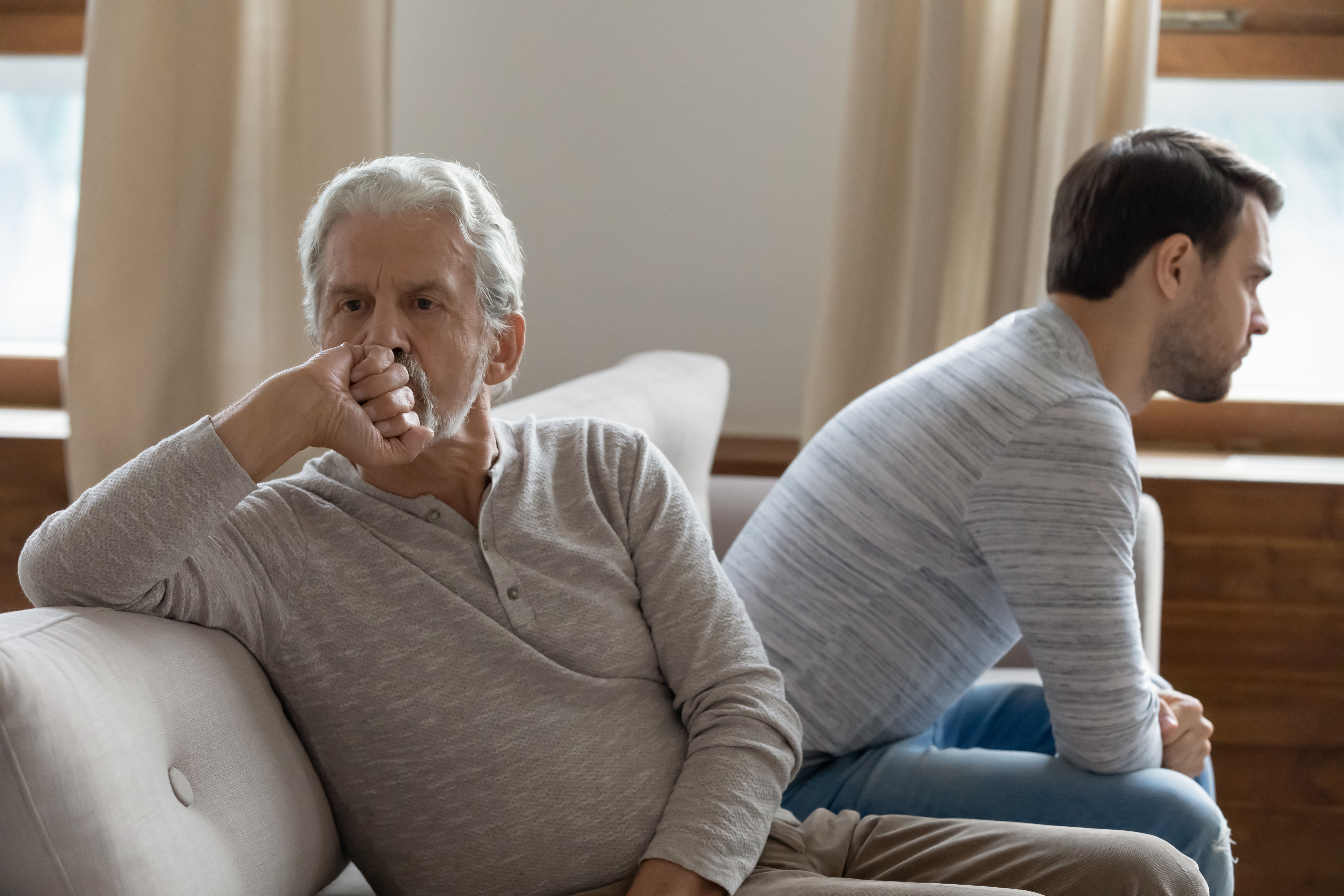 Ein unglücklicher älterer Mann, der einem jüngeren Mann gegenübersitzt | Quelle: Shutterstock