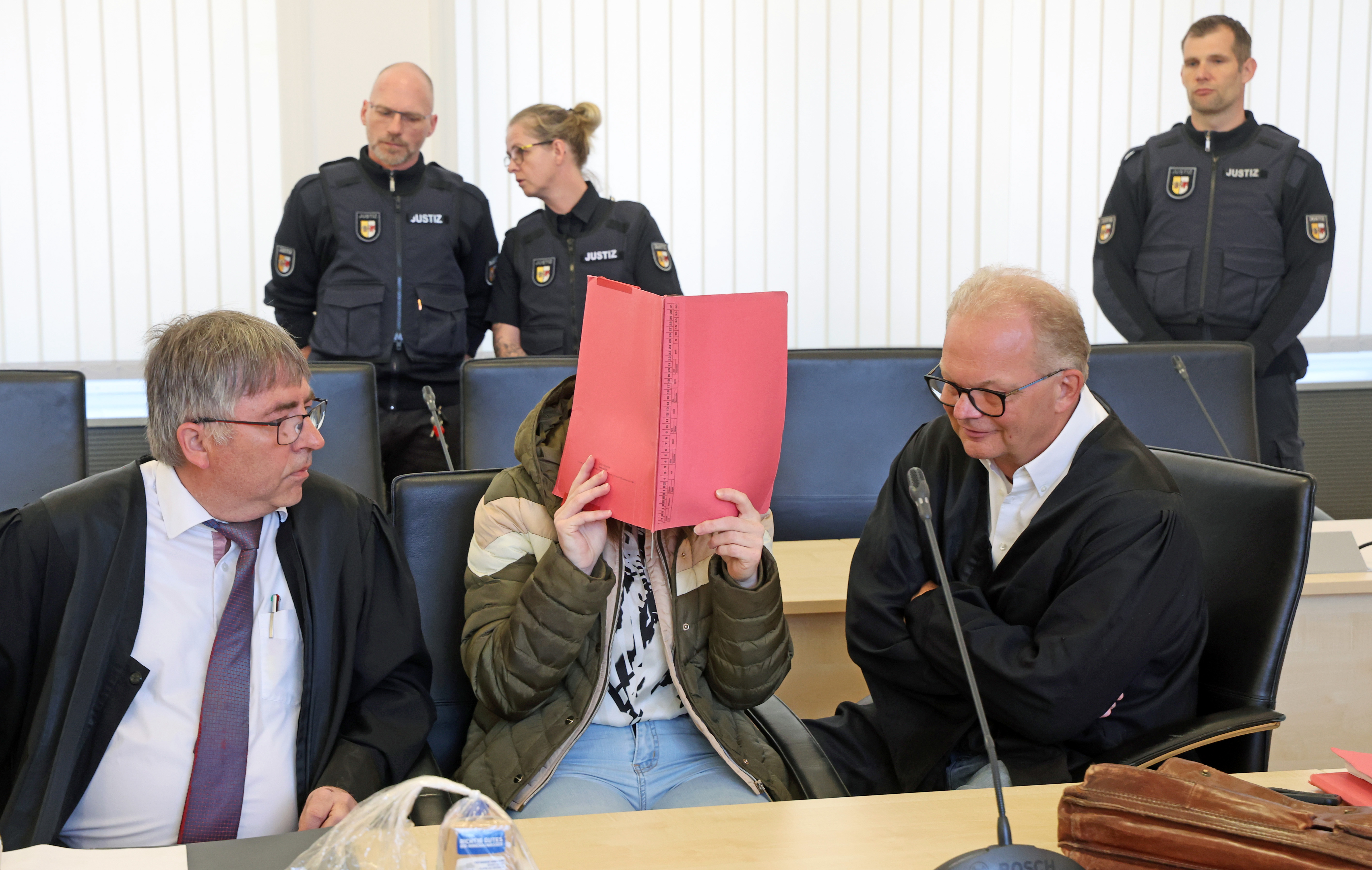 Die Angeklagte verbirgt ihr Gesicht beim Prozessauftakt am 28. April 2026 in Rostock ihr Gesicht hinter einem roten Ordner. | Quelle: Getty Images