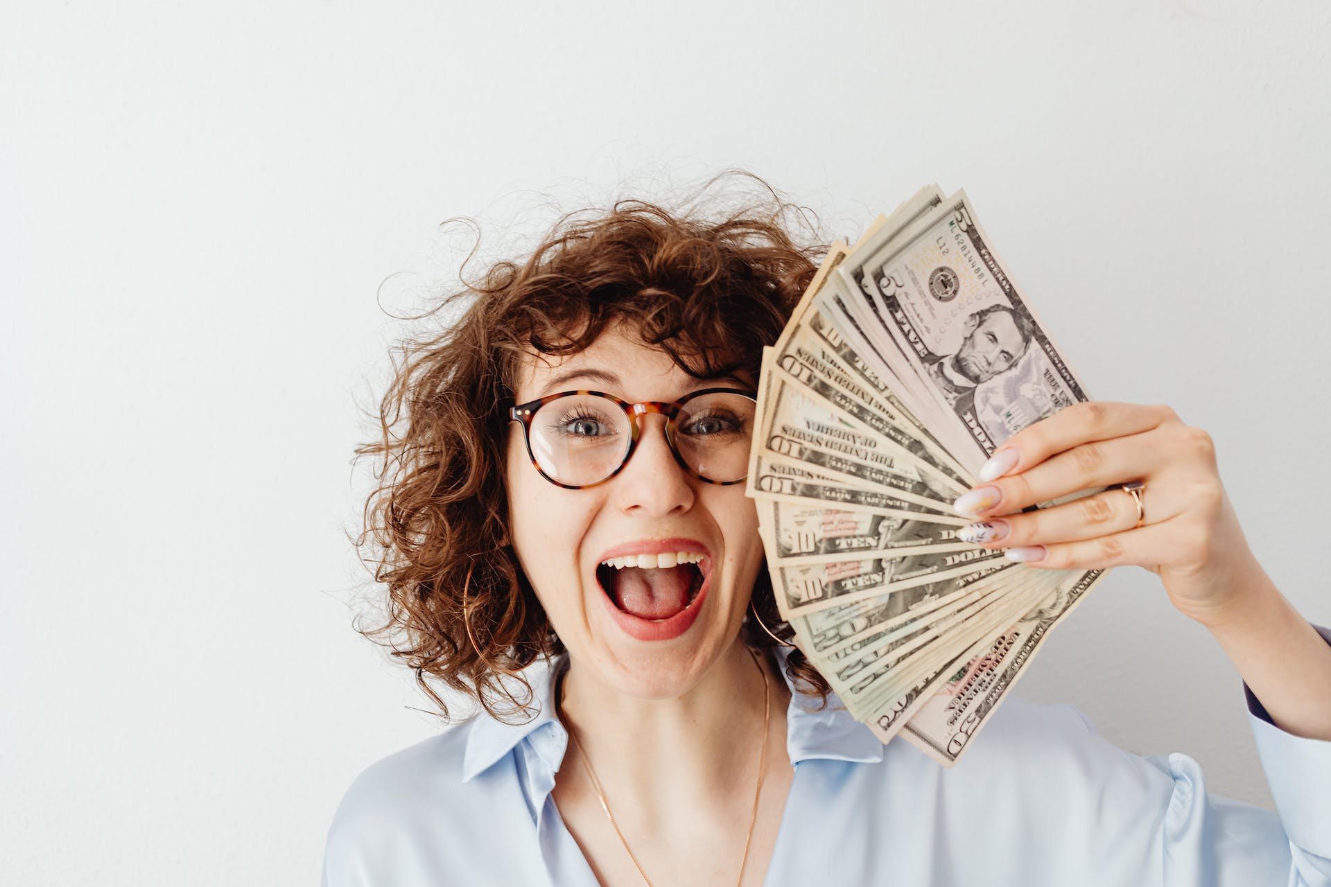 Eine glückliche Frau mit Dollarscheinen in der Hand | Quelle: Pexels
