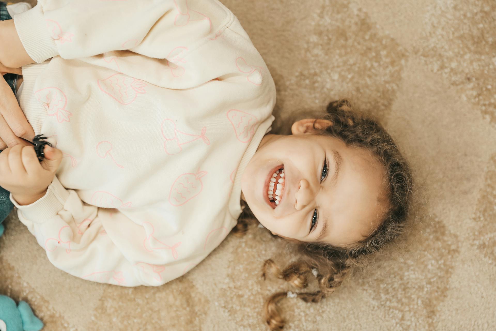 Ein lächelndes Kind, das auf dem Boden liegt | Quelle: Pexels