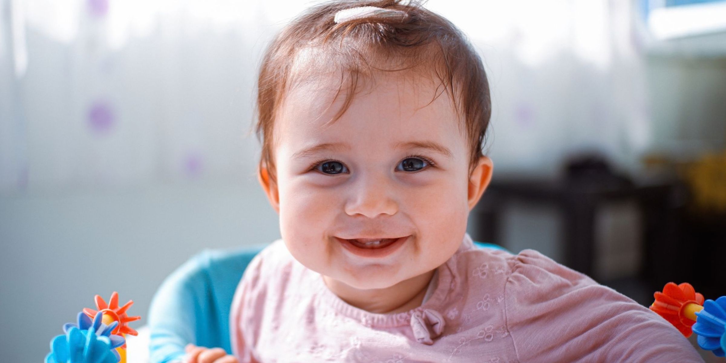 Lächelndes Baby, das in einem bunten Spielsitz sitzt | Quelle: Pexels