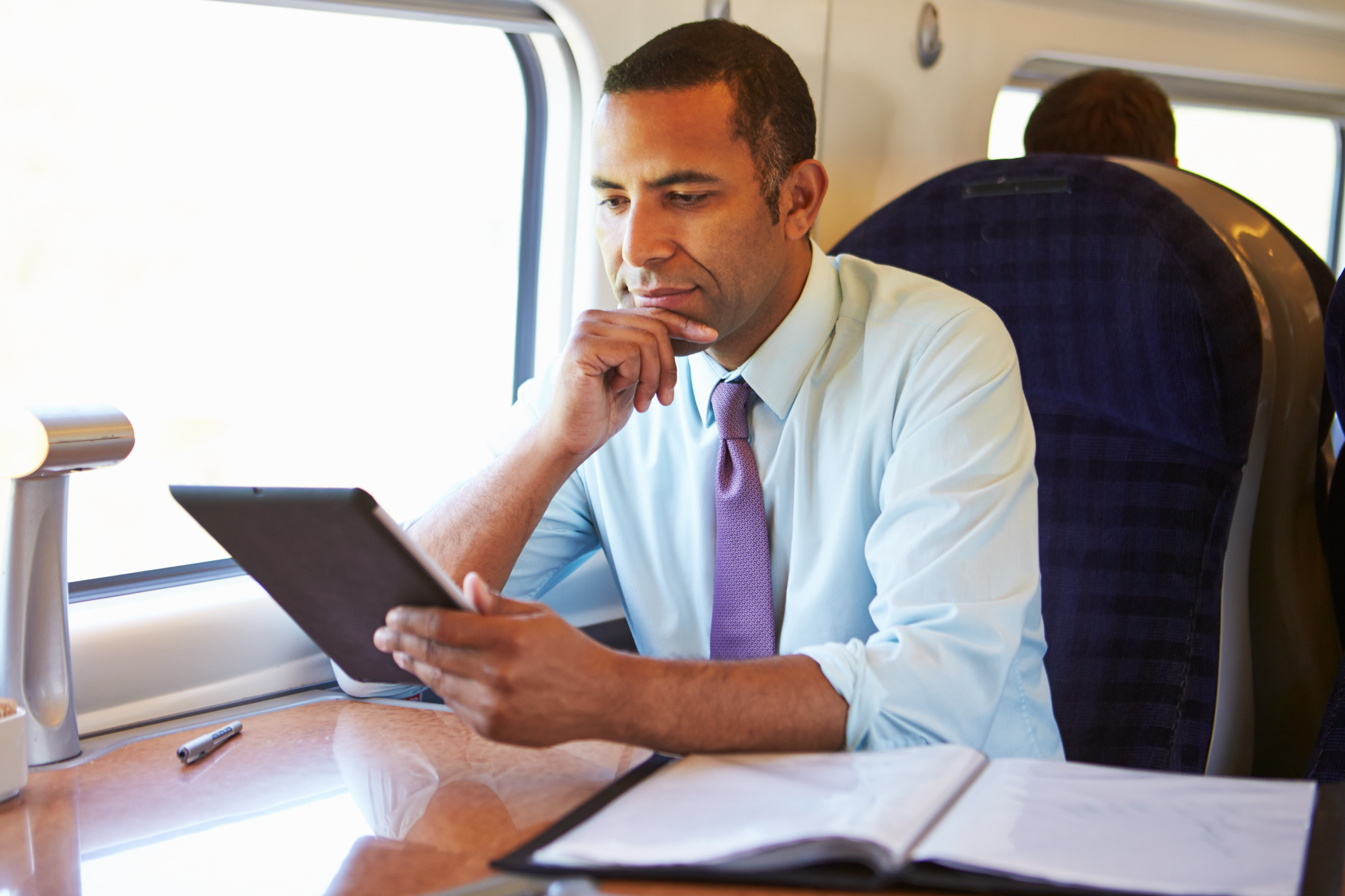 Ein Mann sitzt auf einem Fensterplatz in einem Zug | Quelle: Shutterstock