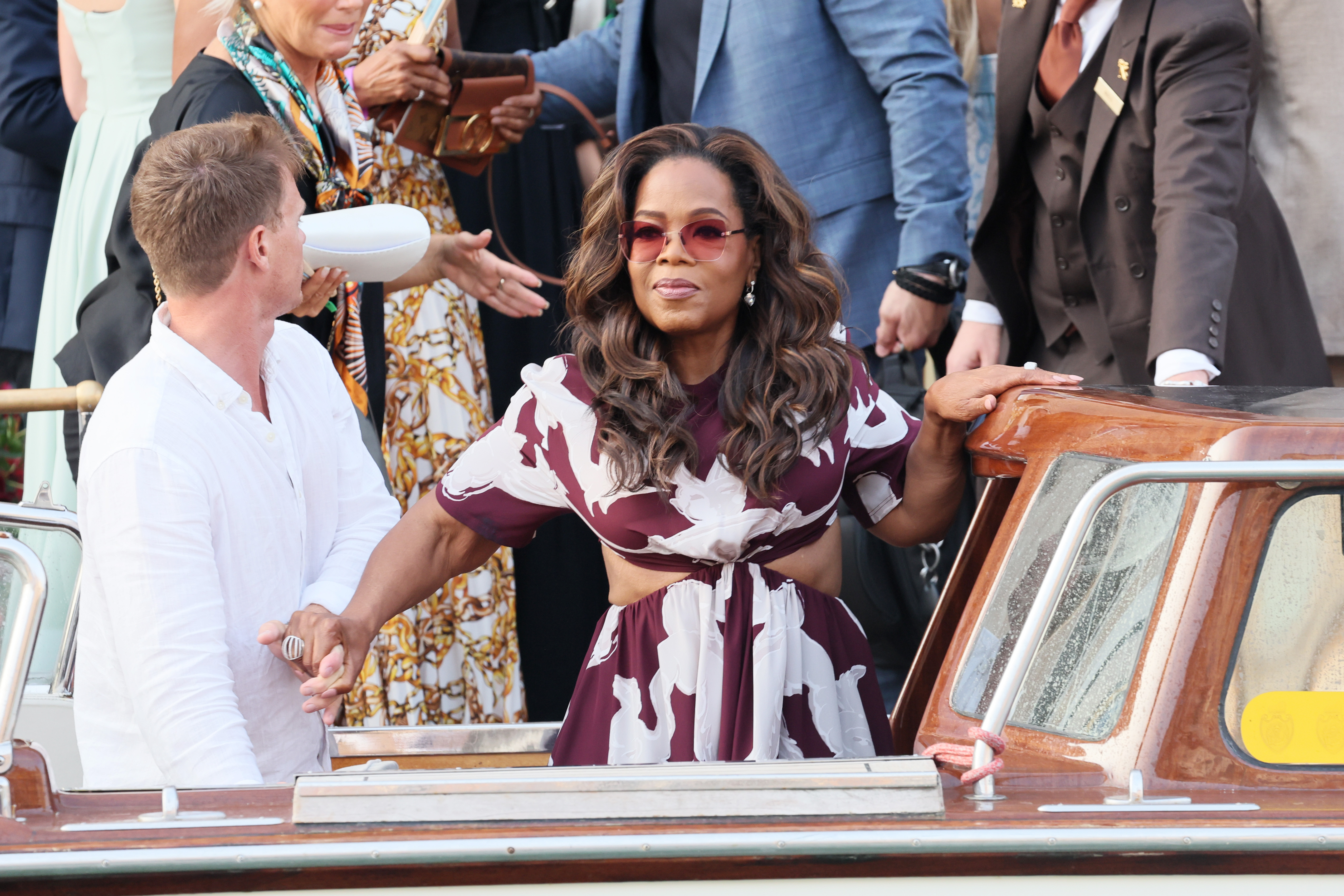 Oprah Winfrey wird fotografiert, wie sie sich am Taxibootführer festhält, während sie leicht lächelt. Dieses Foto wurde vor der Hochzeit von Bezos und Sanchez in Italien aufgenommen.