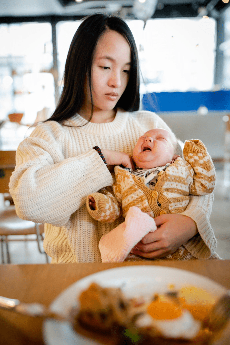 Mutter hält ihr Baby im Café. | Quelle: Getty Images