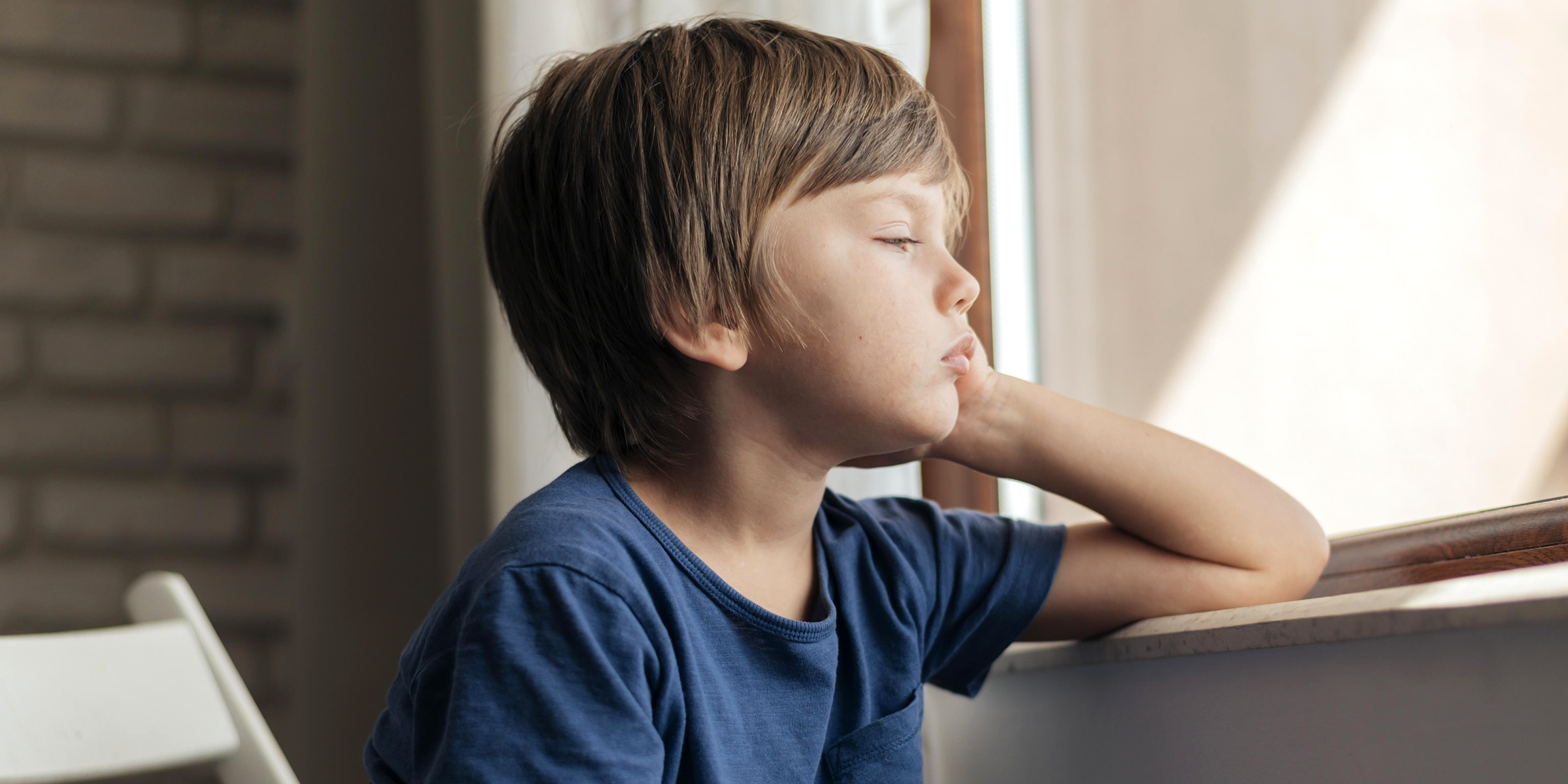 Ein mürrischer Junge, der aus dem Fenster starrt | Quelle: Freepik