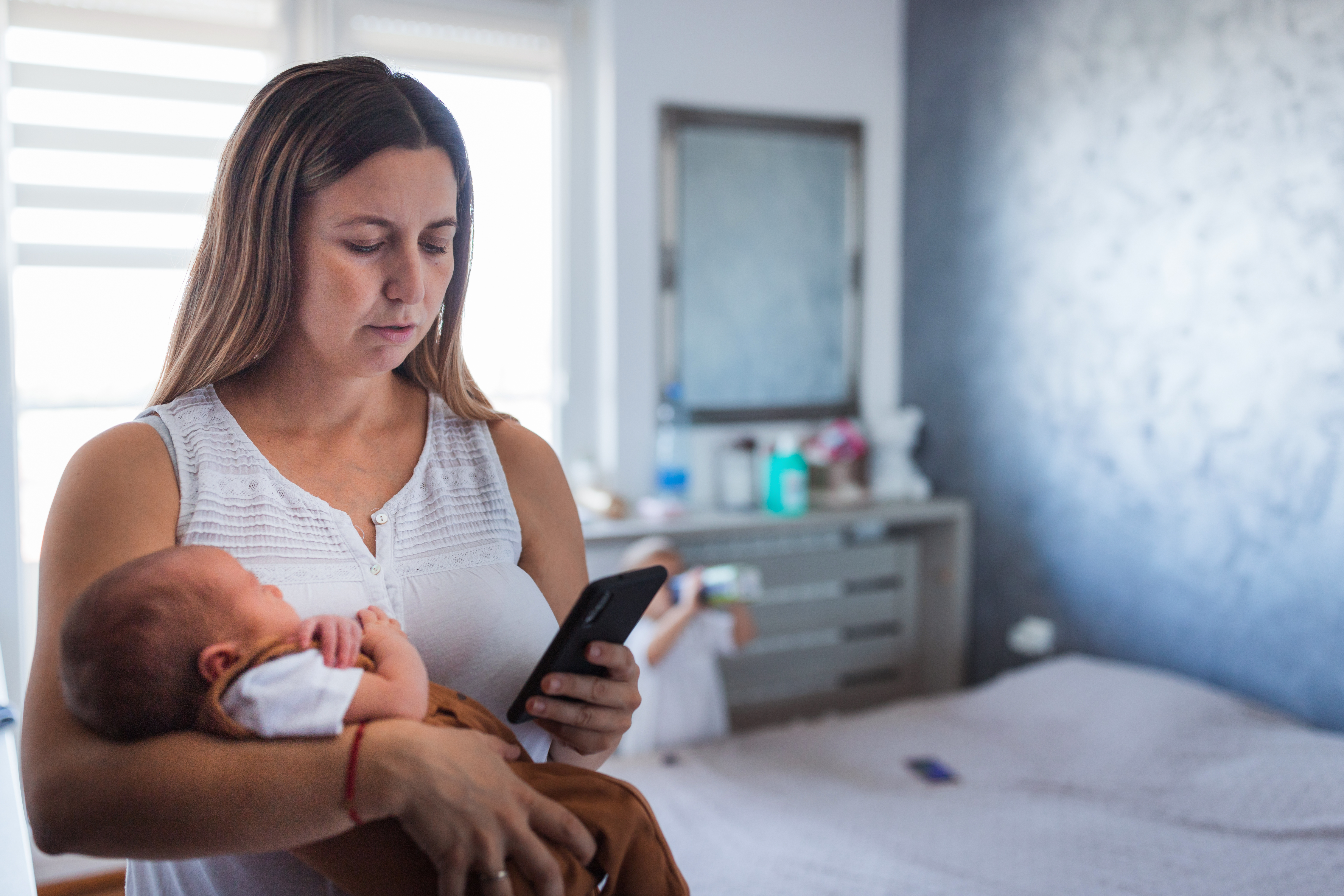 Eine Frau hält ein Baby, während sie auf ihr Telefon schaut | Quelle: Getty Images