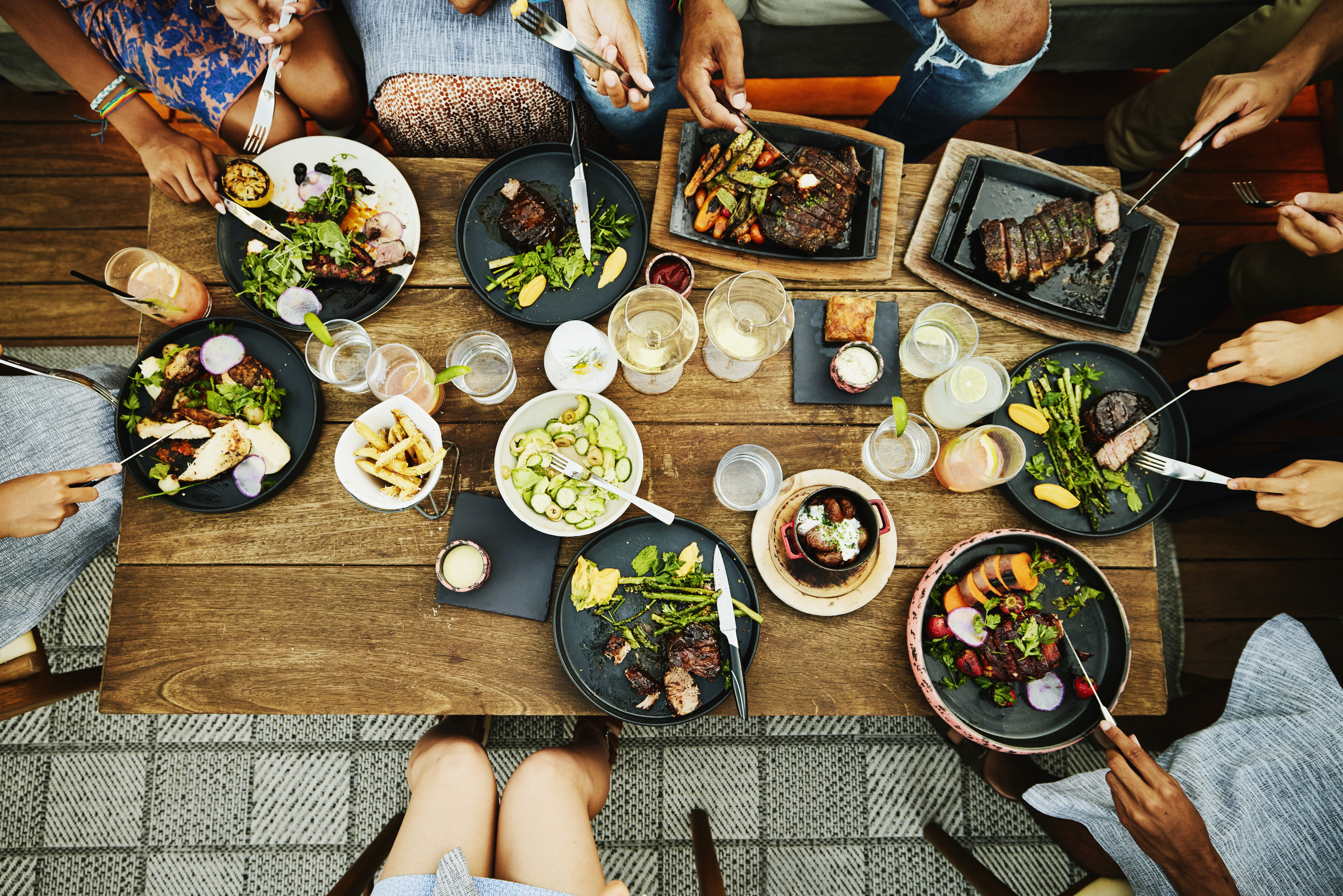 Familienmitglieder beim gemeinsamen Abendessen in einem Restaurant im Freien | Quelle: Getty Images