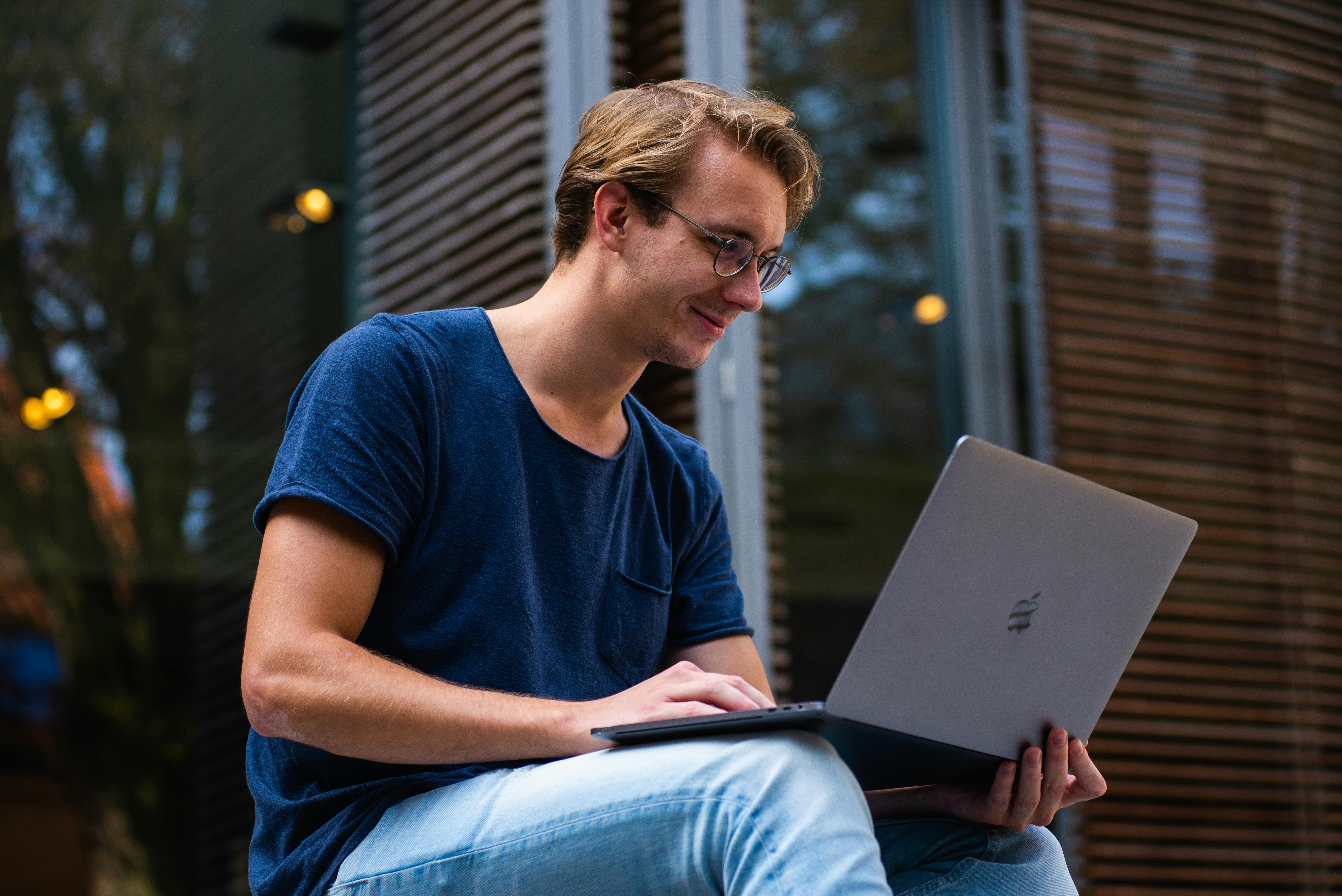 Um homem sorridente com um laptop | Fonte: Pexels