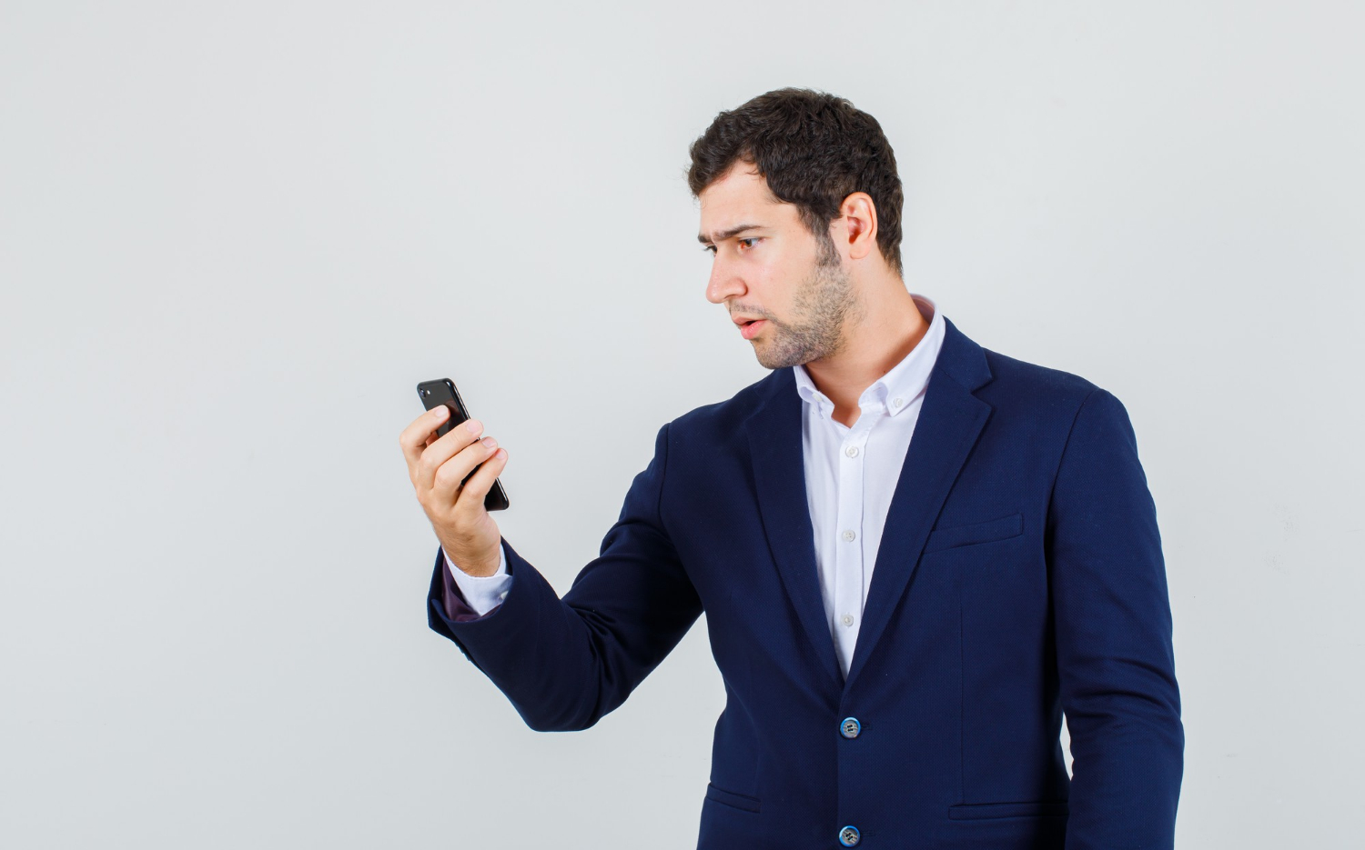 Ein erschrockener junger Mann, der auf ein Telefon schaut | Quelle: Freepik