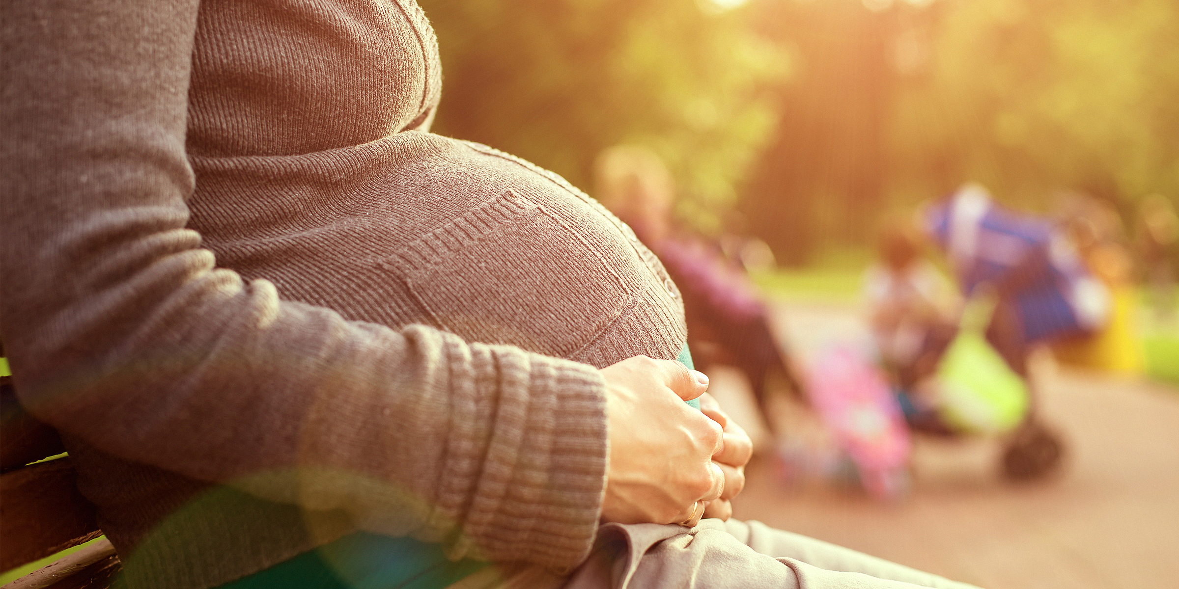 Eine schwangere Frau, die ihren Babybauch im Sitzen streichelt | Quelle: Shutterstock