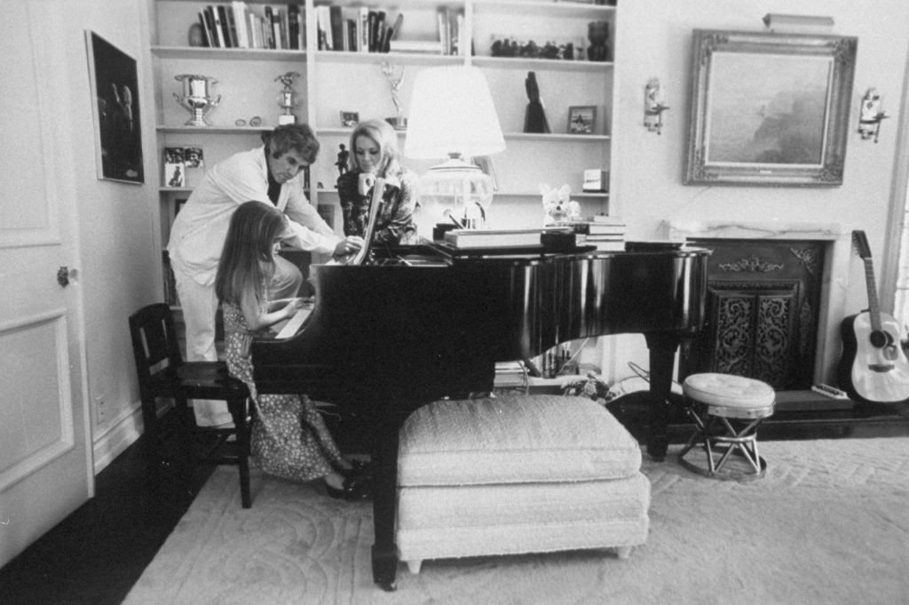 Komponist Burt Bacharach Jr. (L) und seine Schauspielerin Frau Angie Dickinson beobachten ihre Tochter beim Klavierspielen. | Quelle: Getty Images