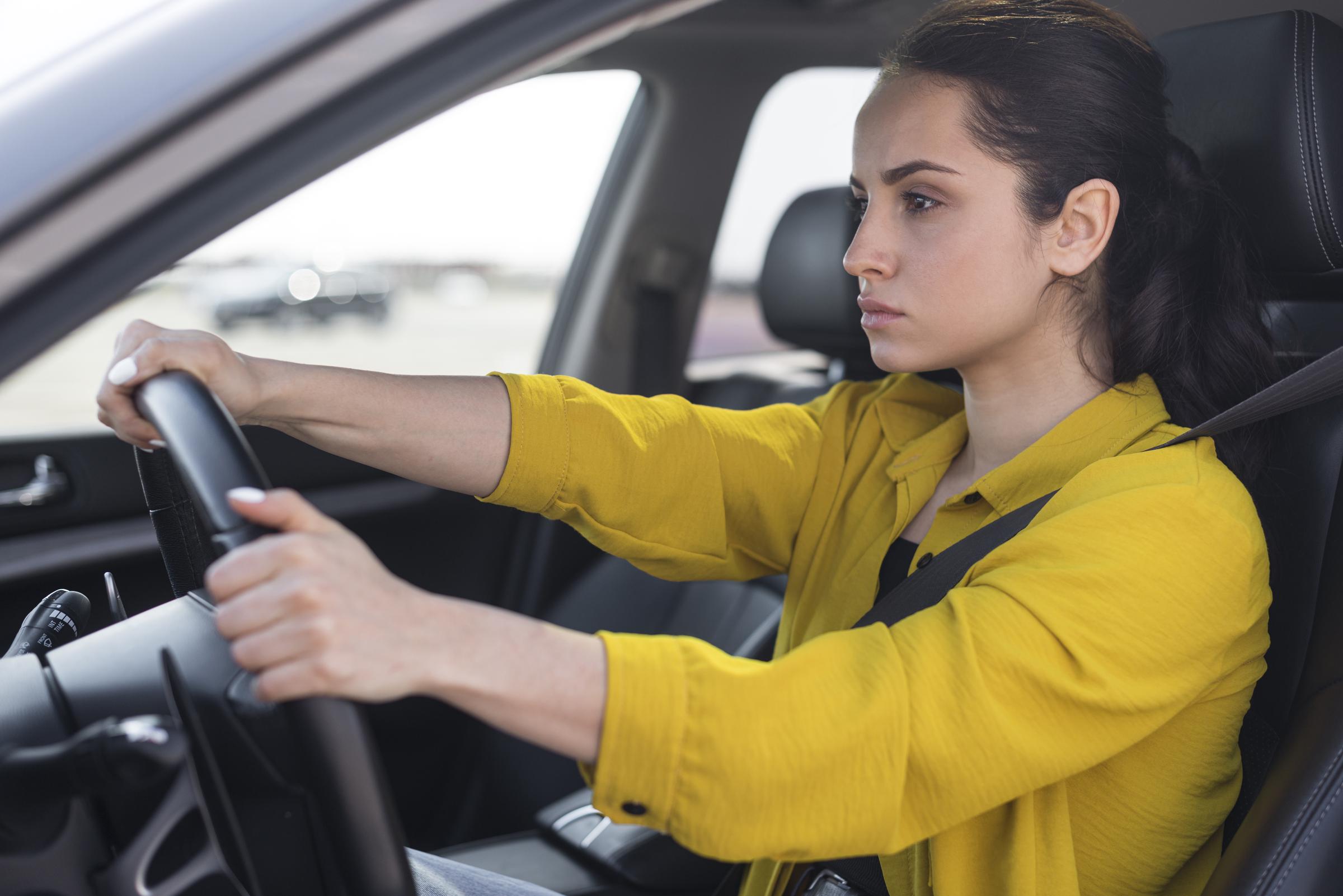 Eine frustrierte junge Frau am Steuer eines Autos | Quelle: Freepik