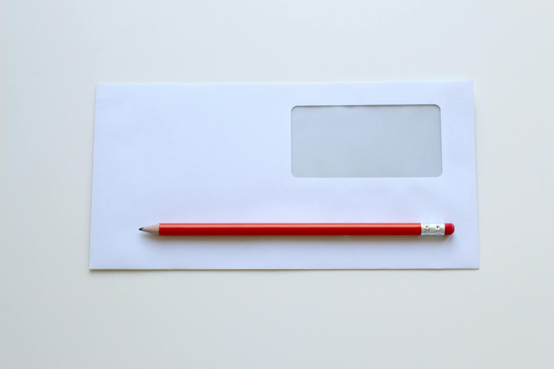 Ein roter Bleistift auf einem weißen Fensterumschlag | Quelle: Pexels