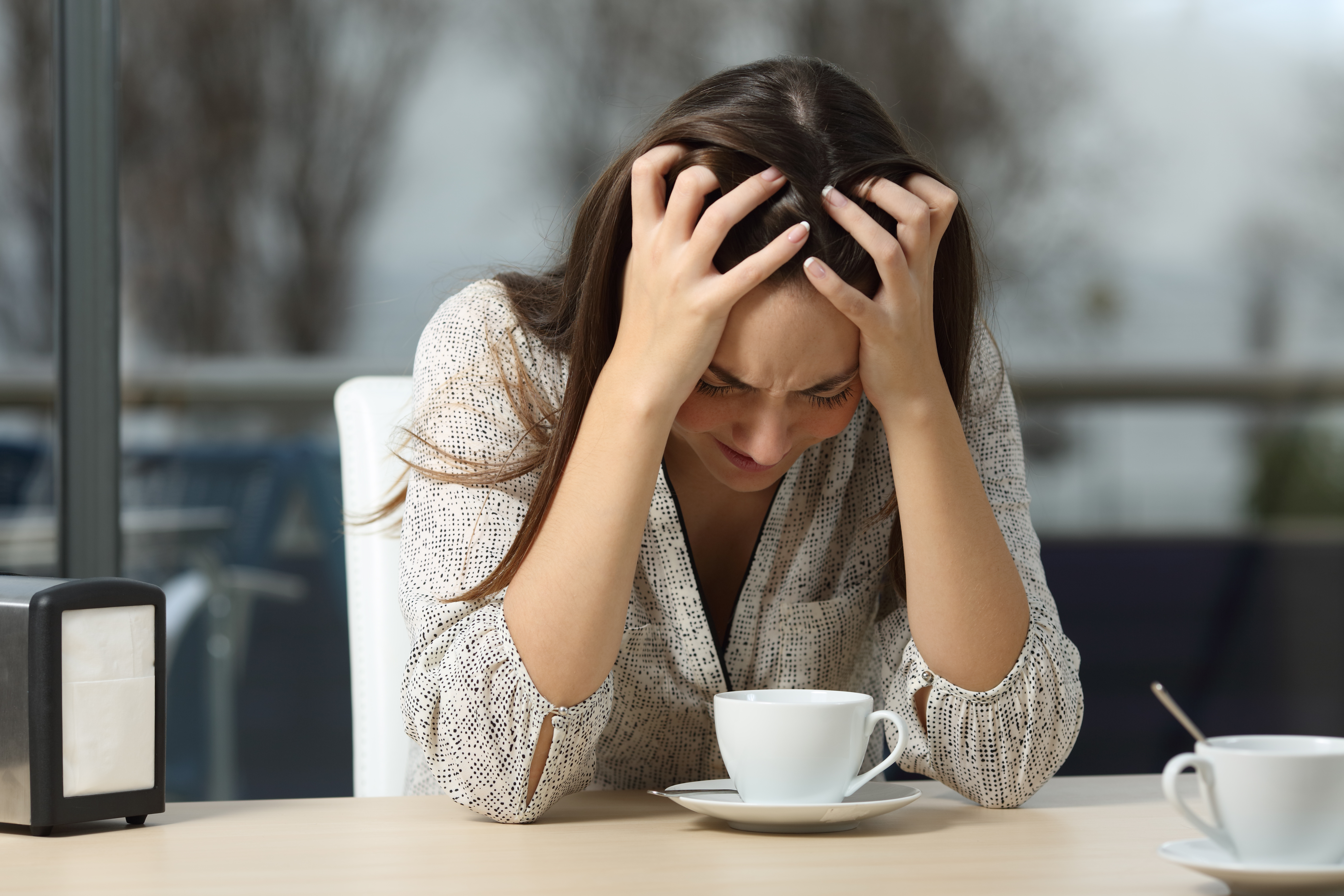 Depressive Frau, die allein in einem Café sitzt | Quelle: Shutterstock