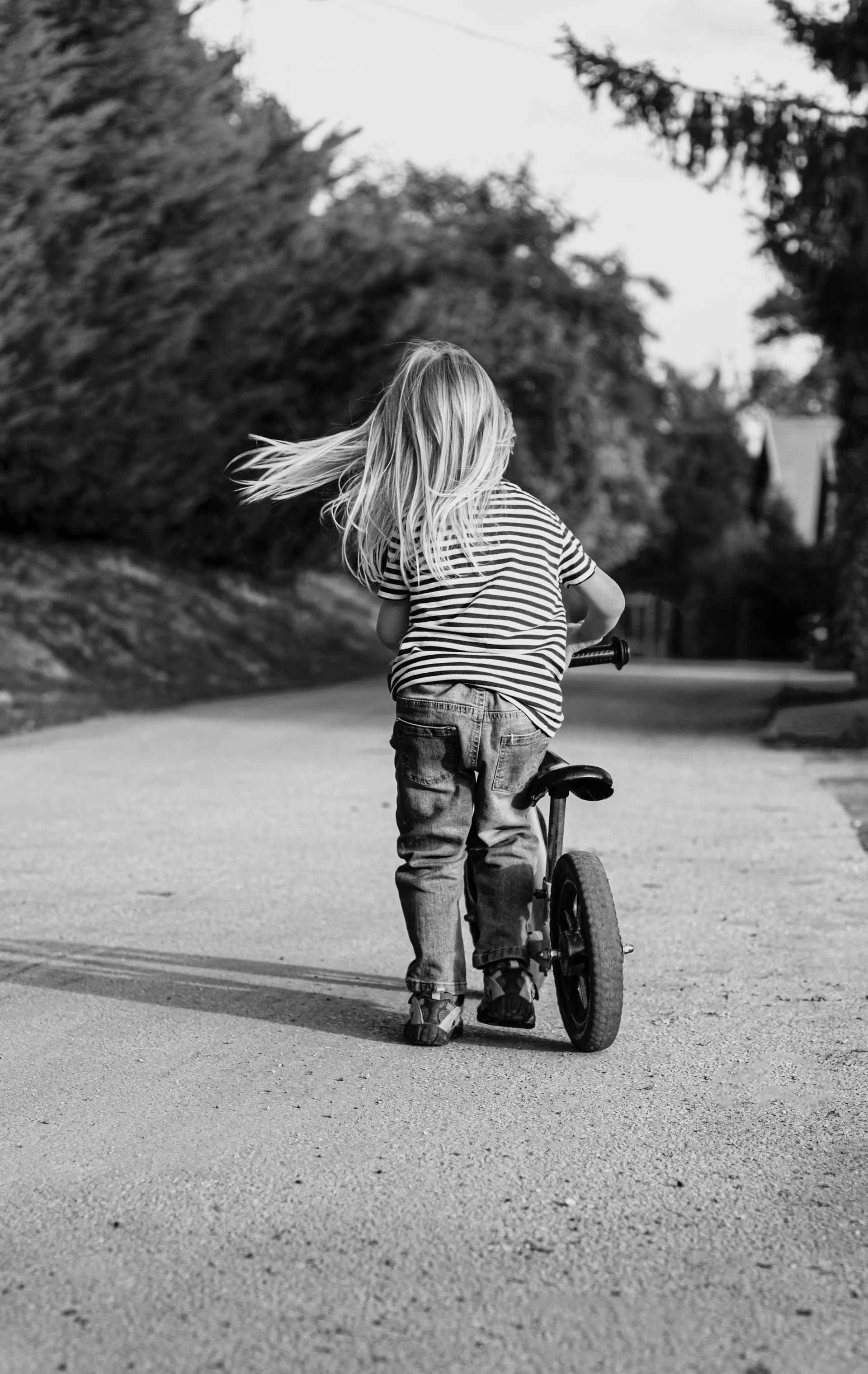 Graustufenaufnahme eines kleinen Mädchens beim Fahrradfahren | Quelle: Pexels