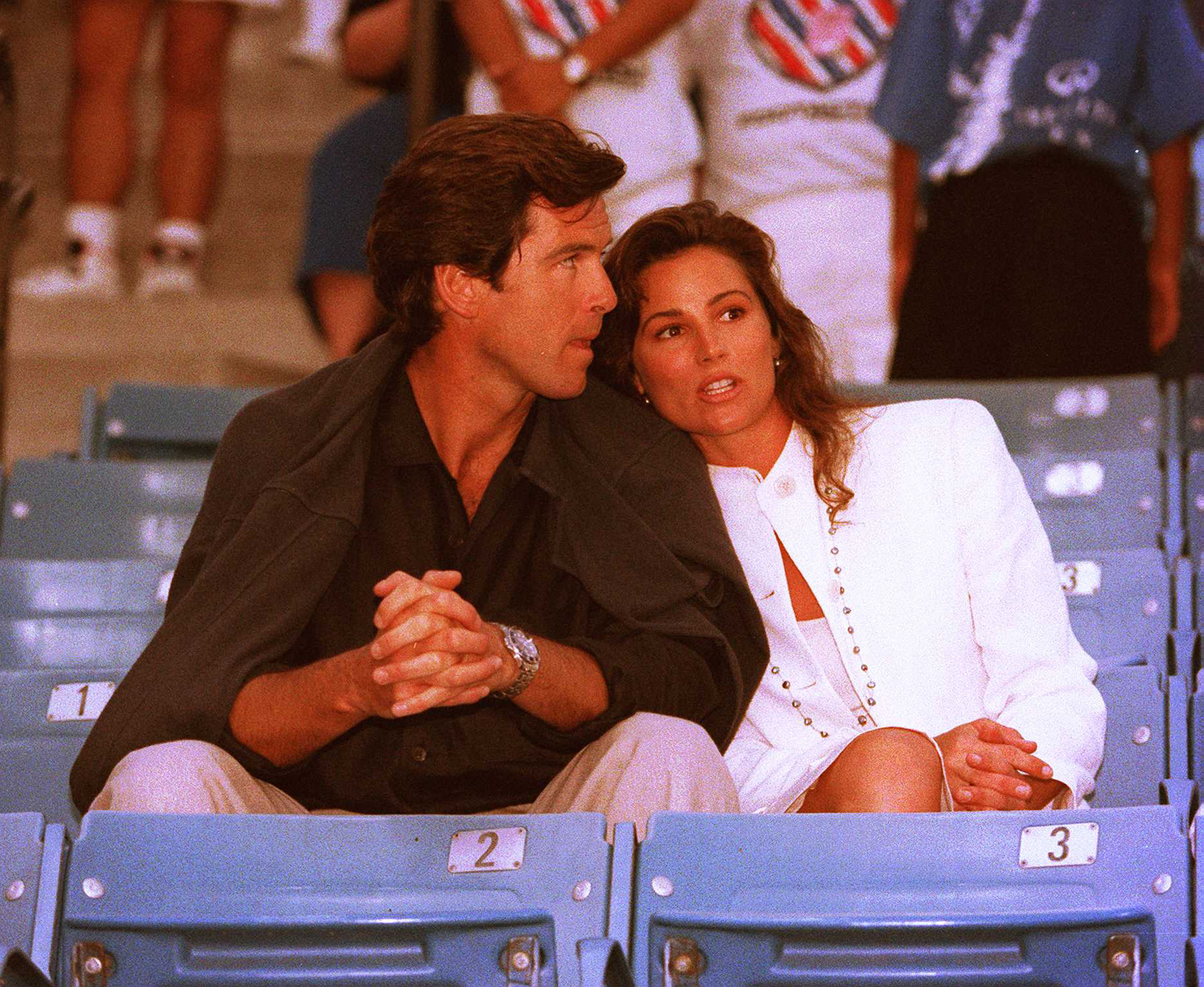 Pierce Brosnan und Keely Shaye Smith hatten einen innigen Moment, als sie am 31. Juli 1995 das Infiniti-Tennisturnier in Westwood, Kalifornien, verfolgten. | Quelle: Getty Images.