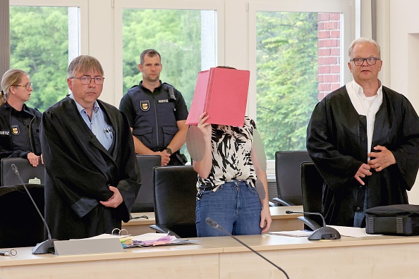 Andreas Ohm (l.), die Angeklagte und Thomas Löcker erheben sich im Gerichtssaal des Landgerichts Rostock zur Fortsetzung des Mordprozesses im Fall Fabian, 9. Juni 2026. | Quelle: Getty Images