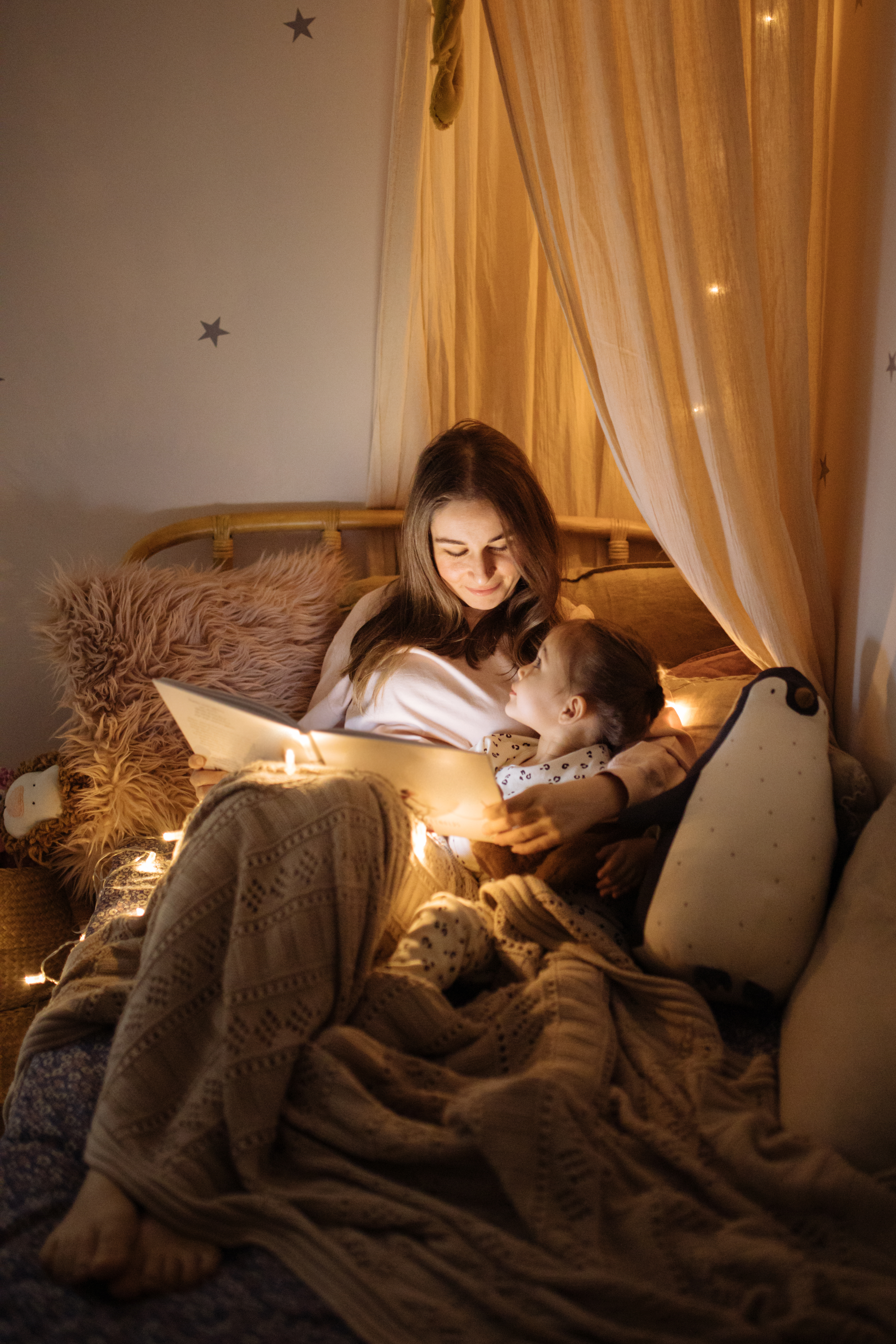 Mutter und Kind lesen ein Buch im Bett, bevor sie schlafen gehen | Quelle: Getty Images