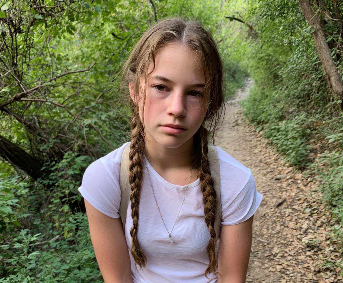 Ein gestresstes Teenager-Mädchen in einem weißen T-Shirt auf einer Wanderung | Quelle: Midjourney
