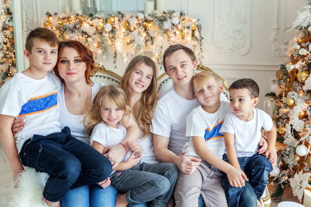Eine glückliche Familie mit einem Vater, einer Mutter und fünf Kindern, die für ein Foto posieren. | Quelle: Shutterstock