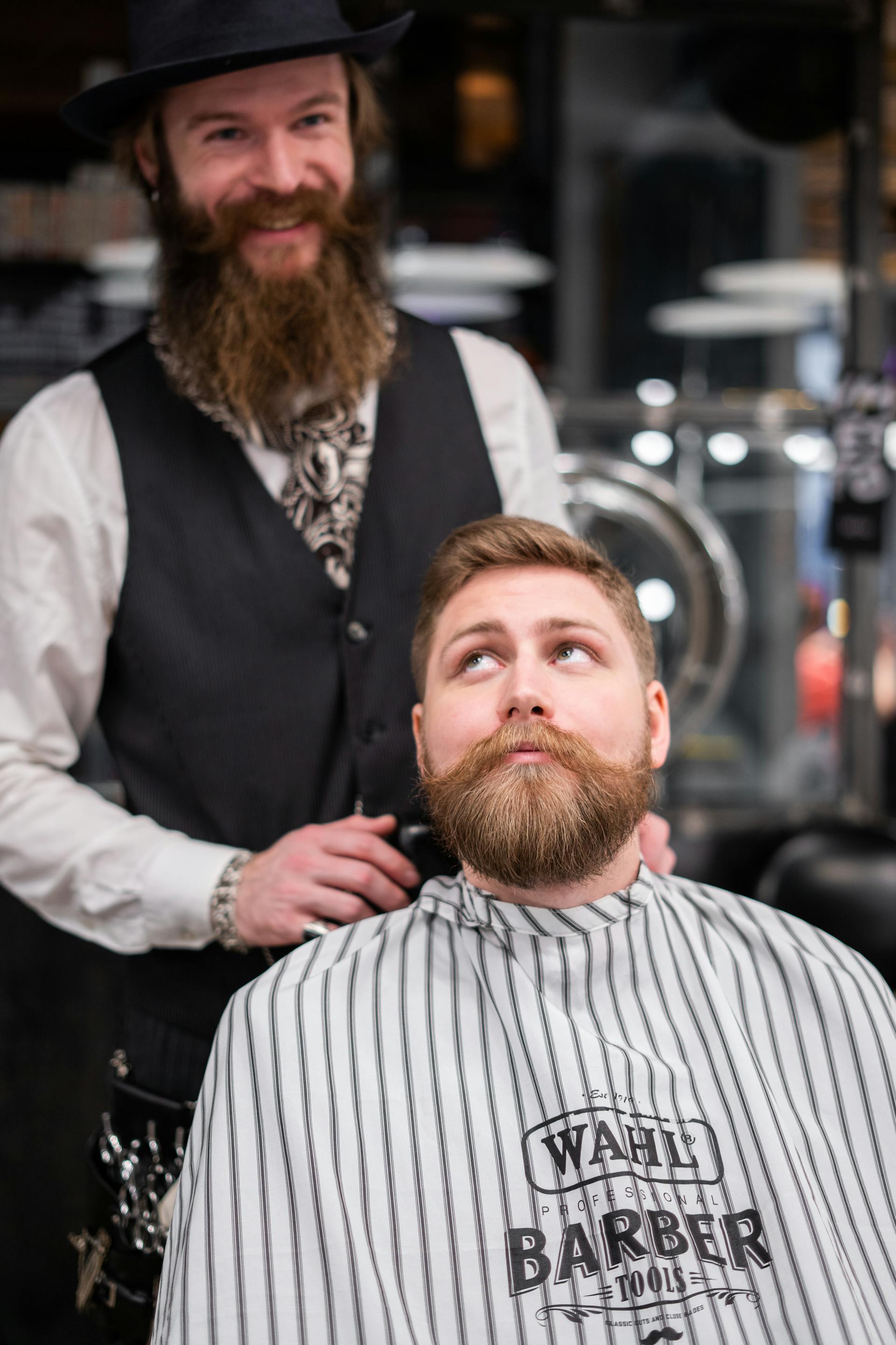 Ein Friseur lächelt, während er hinter einem Kunden in seinem Laden steht | Quelle: Pexels