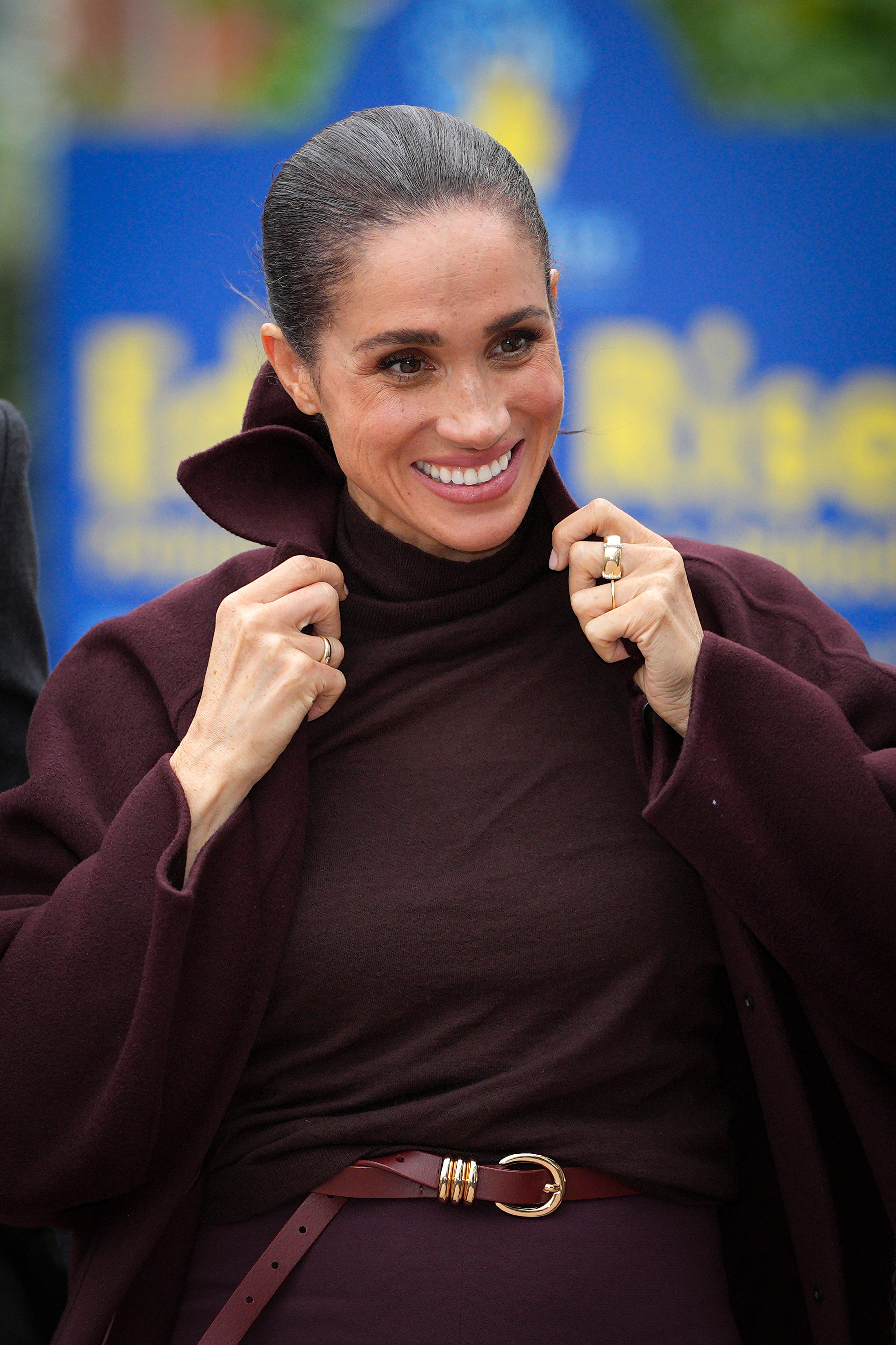 Meghan, Herzogin von Sussex, richtet den hochgeschlagenen Kragen ihres maßgeschneiderten burgunderroten Mantels, als sie am 15. Oktober 2026 bei Epic Partners in Nottingham, England, ankommt. Sie kombiniert den edlen, einfarbigen Look mit einem passenden Rollkragenpullover und einem Gürtel in der Taille. | Quelle: Getty Images