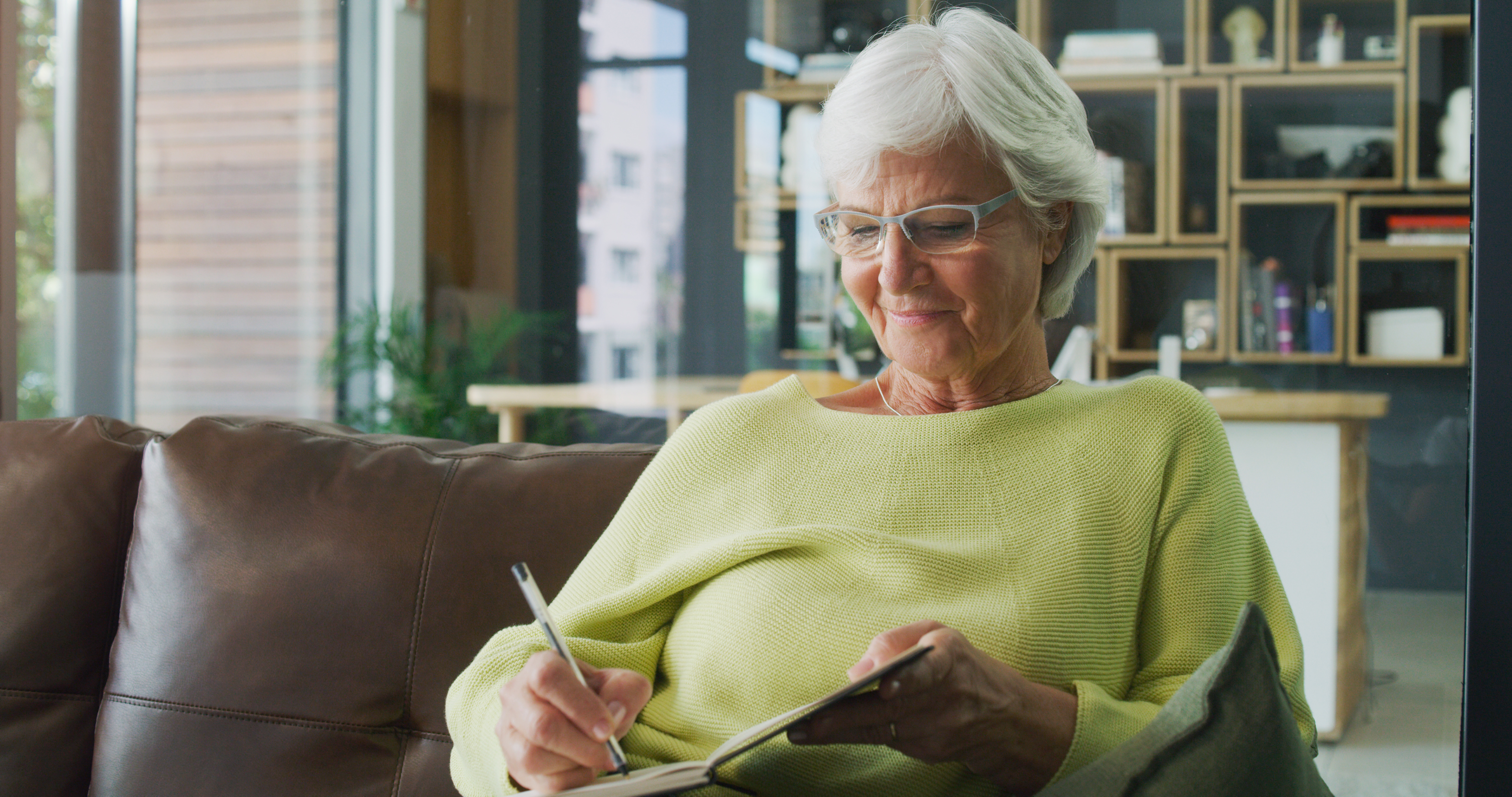 Aufnahme einer älteren Frau, die zu Hause in ein Tagebuch schreibt | Quelle: Getty Images