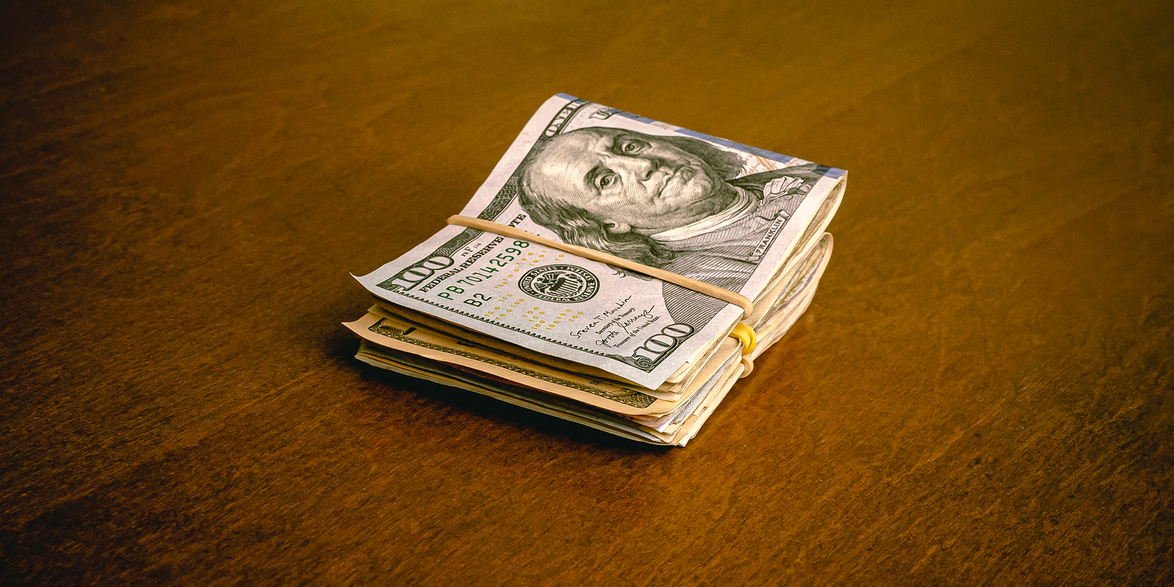 Ein gefalteter Stapel von Dollarscheinen auf einem Tisch | Quelle: Shutterstock