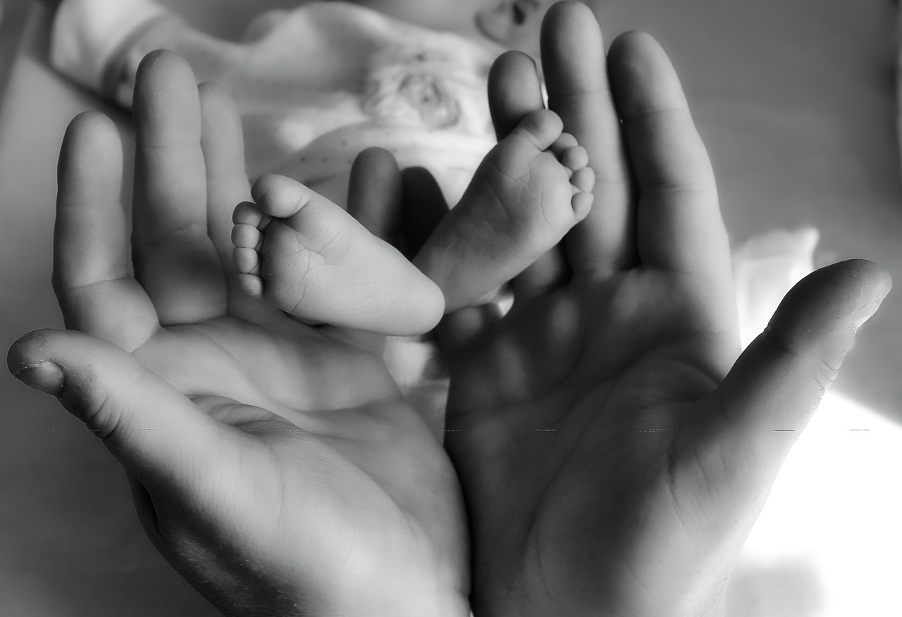Eine Frau hält die Füße eines neugeborenen Babys | Quelle: Pixabay