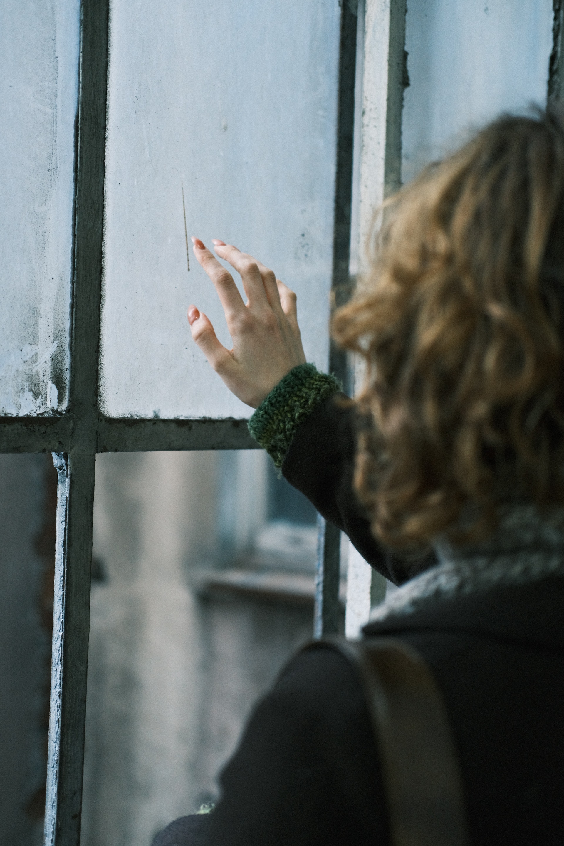 Eine Frau, die ein Glasfenster berührt | Quelle: Pexels