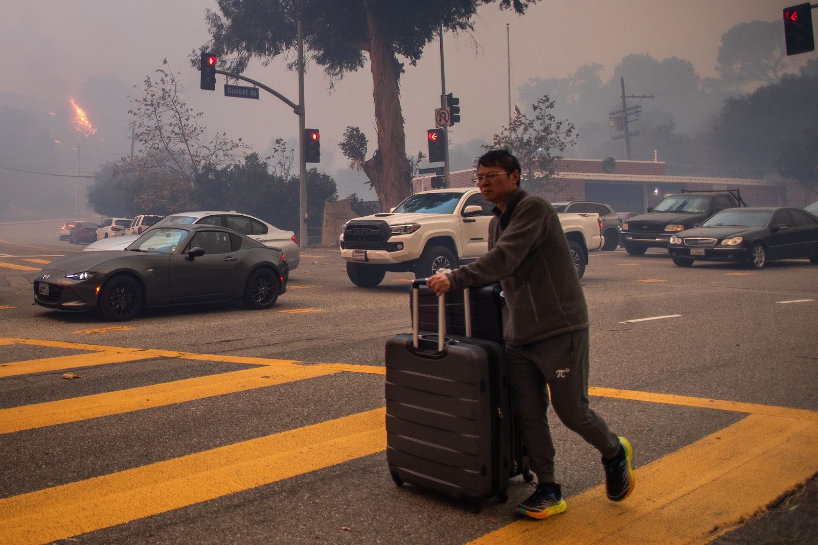 Ein Mann, der den Sunset Boulevard evakuiert, während das Feuer inmitten eines starken Sturms am 7. Januar 2025 im Stadtteil Pacific Palisades von Los Angeles, Kalifornien, brennt. | Quelle: Getty Images