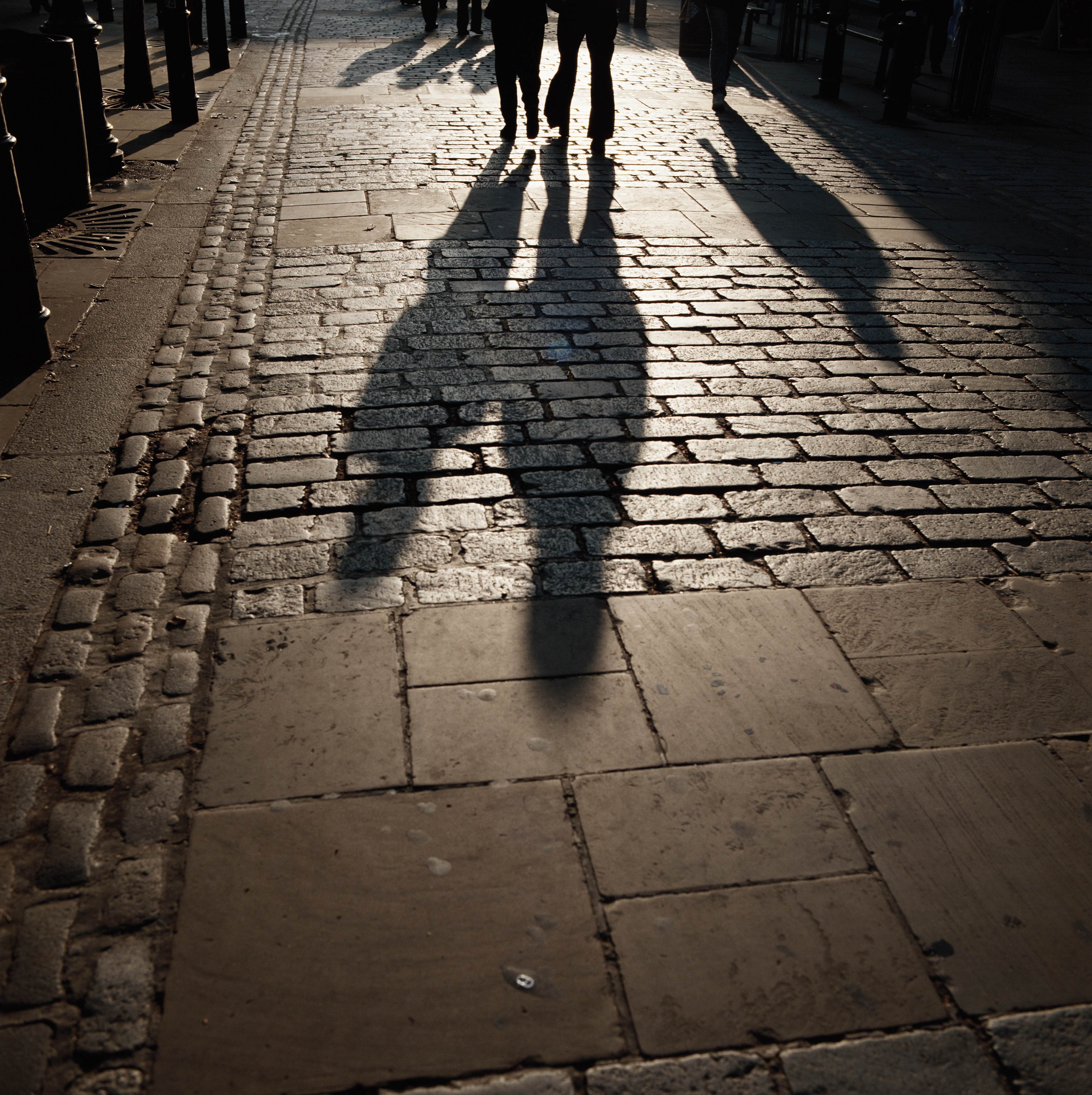 Schatten von Menschen auf dem Fußweg | Quelle: Getty Images