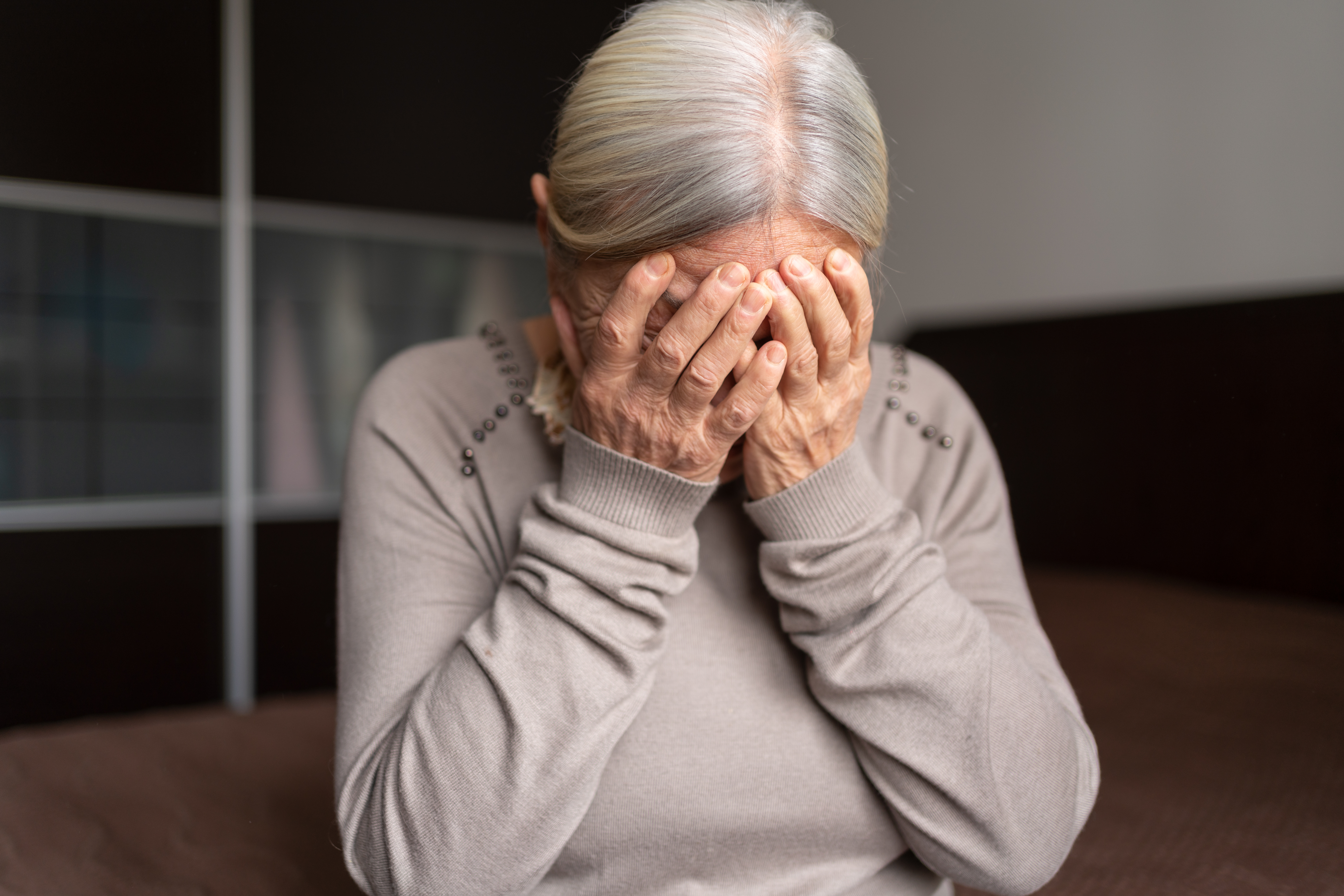 Depressive, einsame ältere Frau bedeckt ihr Gesicht mit beiden Händen | Quelle: Getty Images