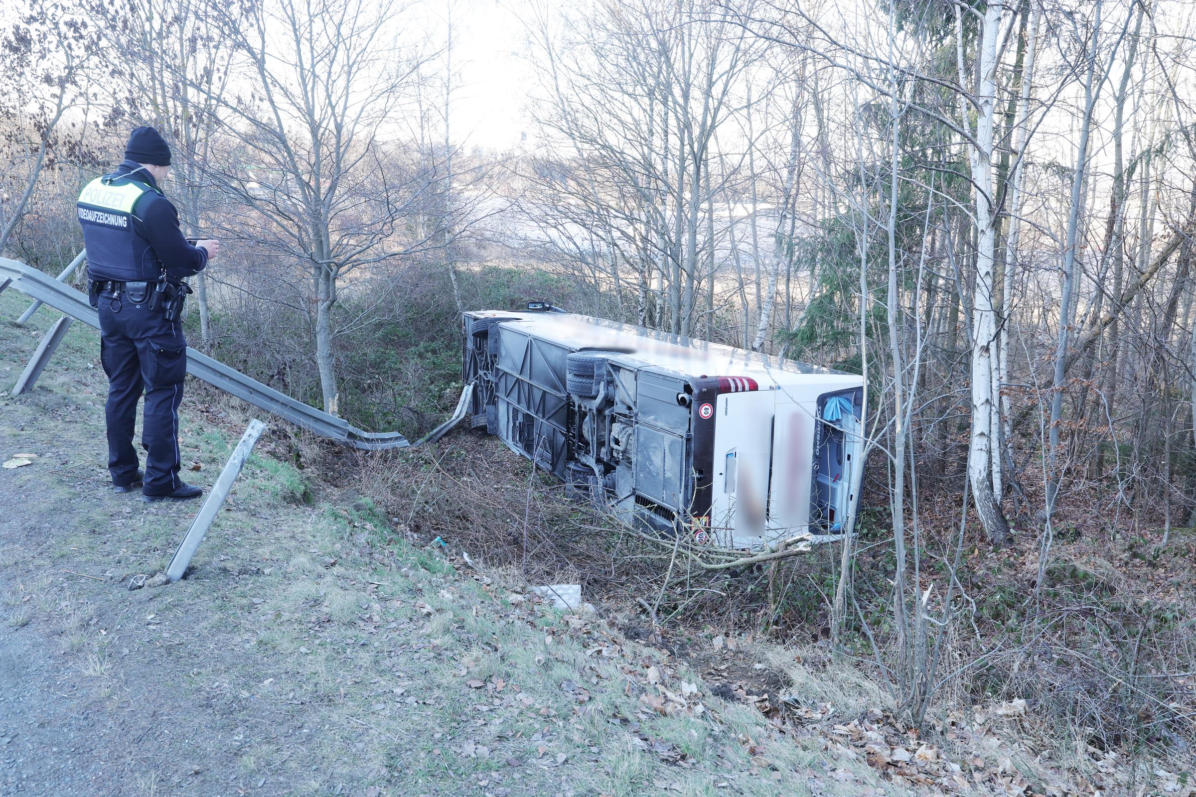 19. Januar 2026, Thüringen, Schleiz: Ein Polizist filmt die Unfallstelle eines Busunglücks mit mehreren Verletzten. Der Reisebus war auf die Seite gekippt und einen Abhang hinuntergerutscht | Quelle: Getty Images