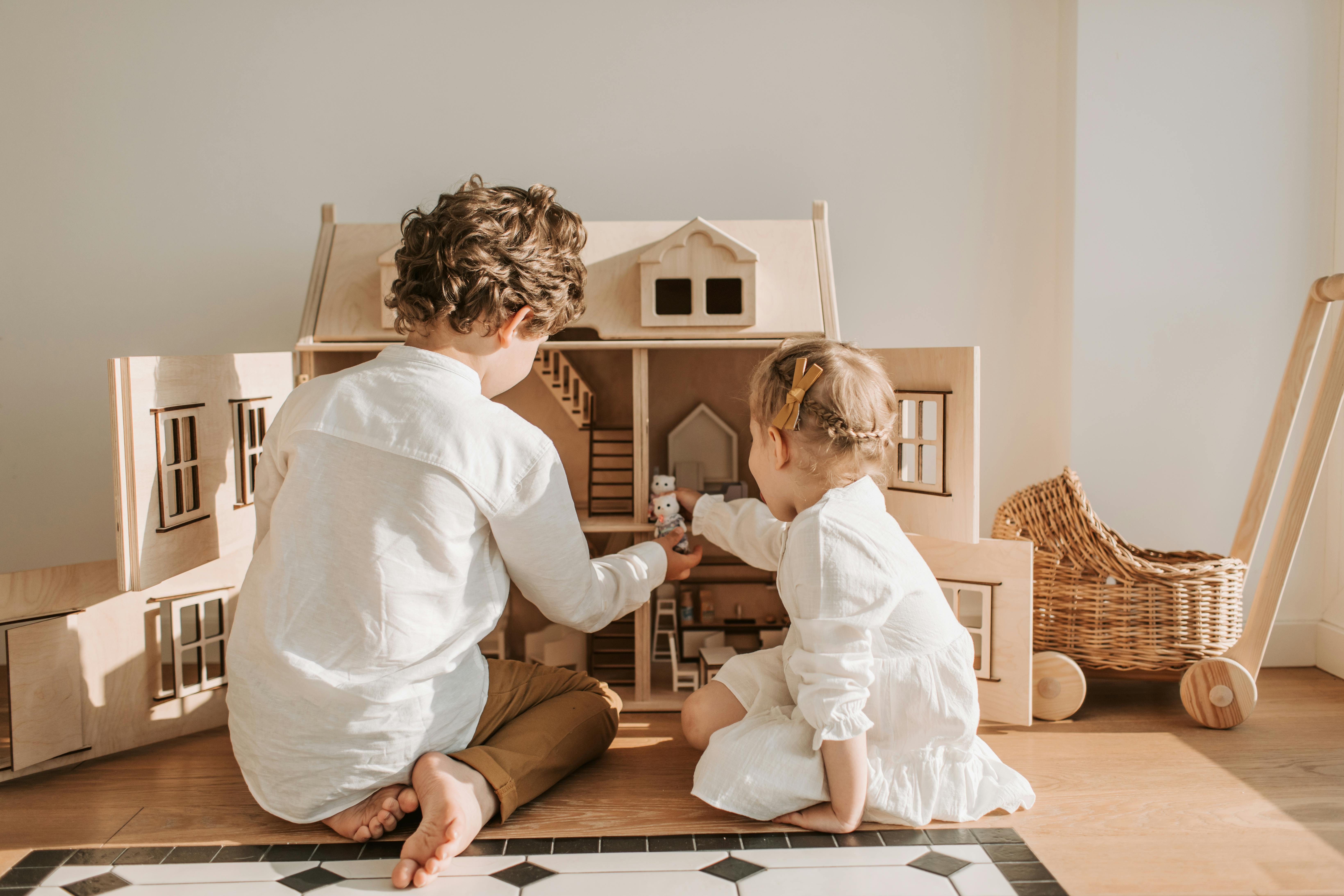 Zwei Kinder spielen mit einem Puppenhaus | Quelle: Pexels