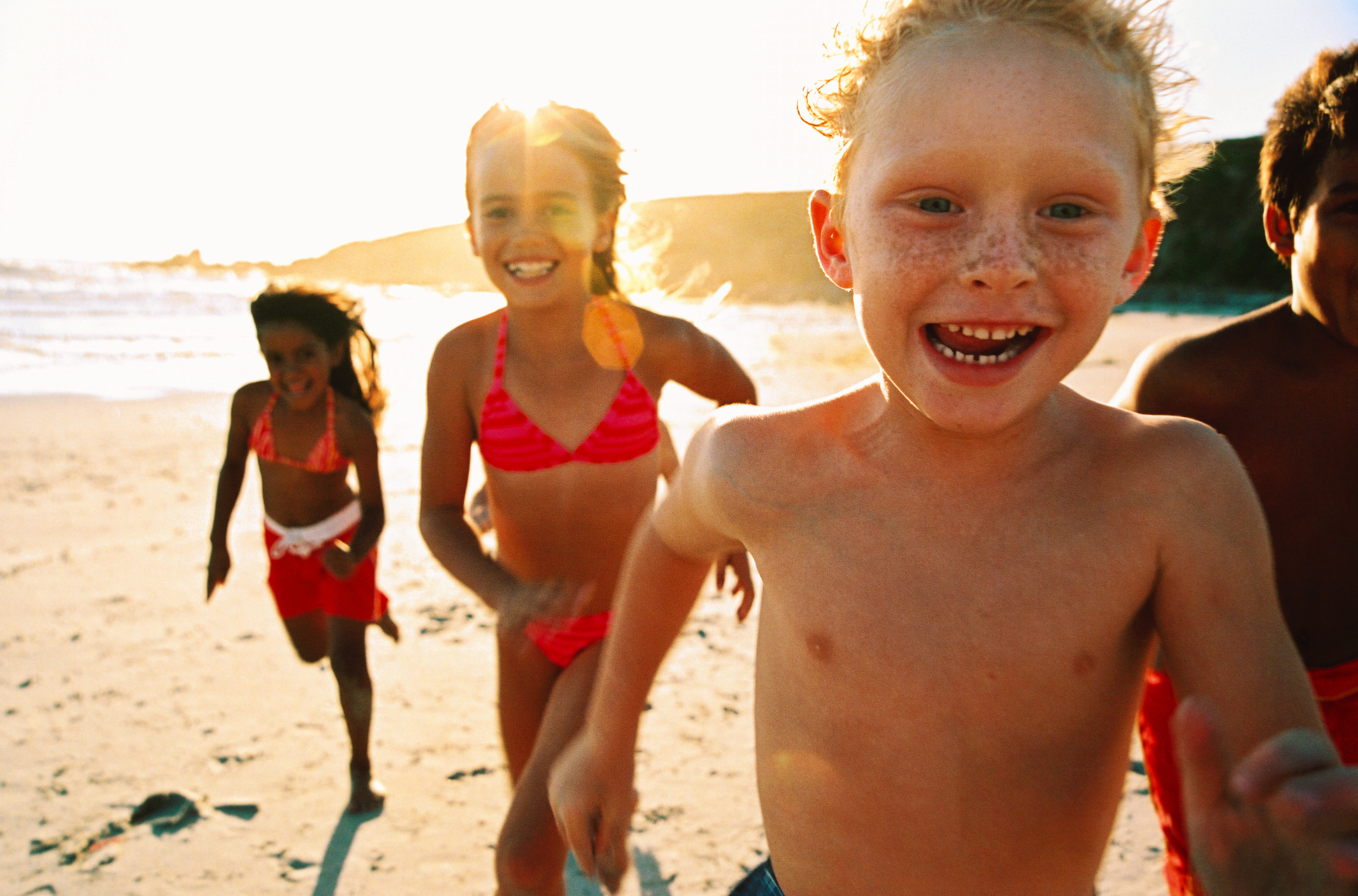 Porträt einer Gruppe von Kindern, die am Strand laufen | Quelle: Getty Images