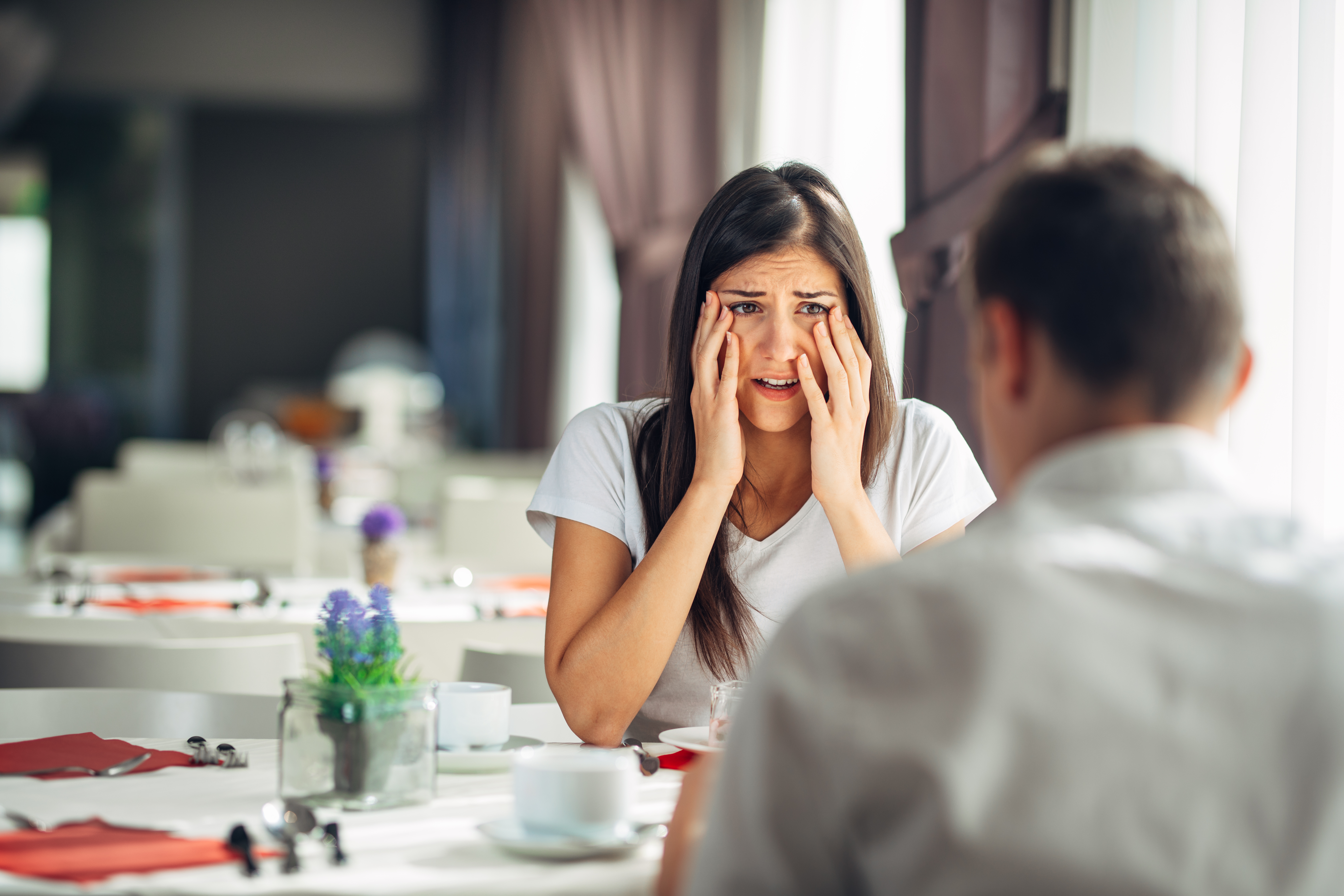 Überrascht blickende Frau beim Essen mit einem Mann | Shutterstock