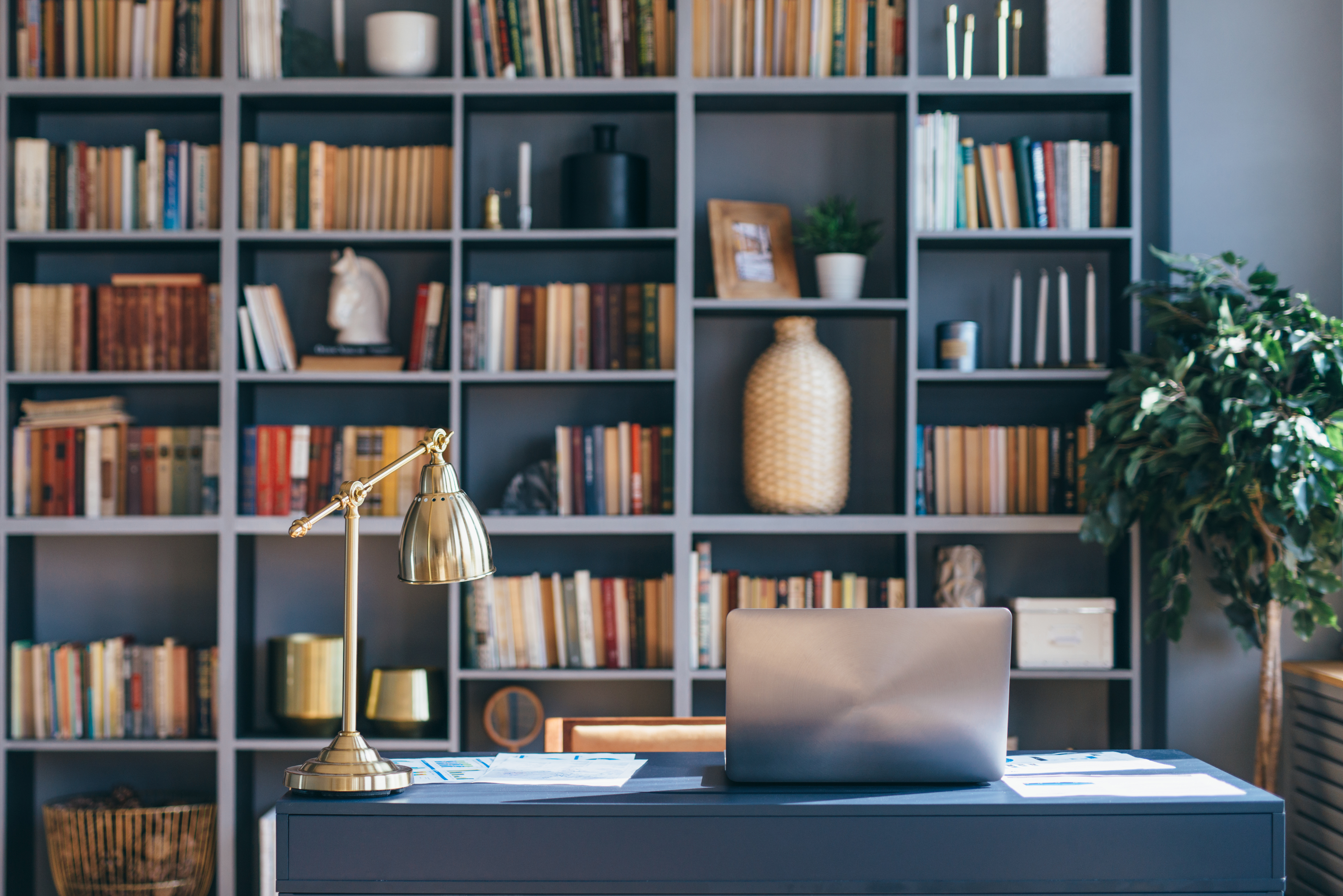 Ein privates Heimbüro mit einem Laptop und einem Regal mit Büchern | Quelle: Shutterstock