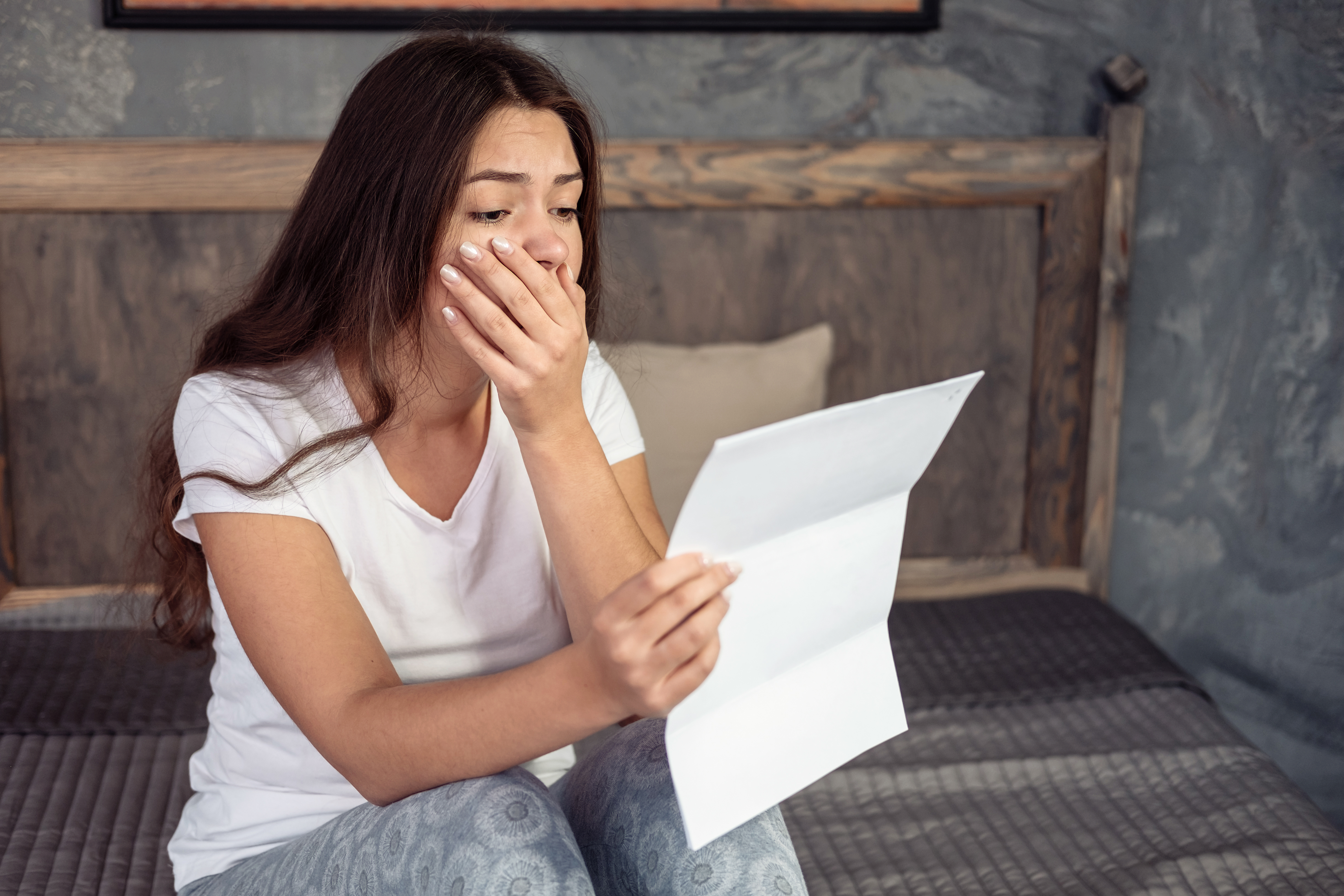 Eine schockierte junge Frau, die einen Brief liest | Quelle: Shutterstock