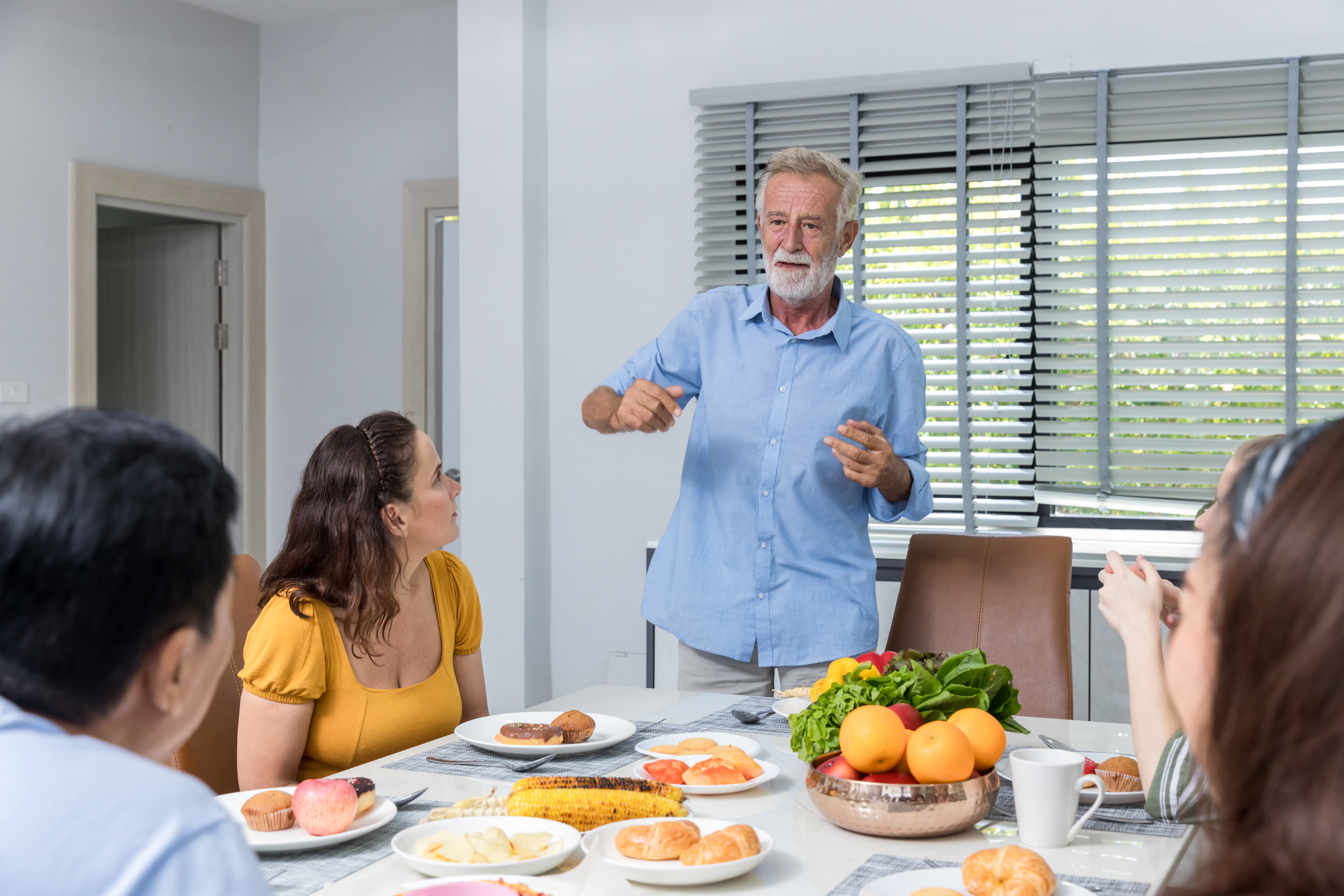 Ein älterer Mann spricht mit seinen Familienmitgliedern am Tisch | Quelle: Shutterstock
